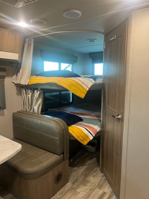 Cozy RV rental interior with bunk beds, dinette seating, and compact design for comfortable travel.. Grand Design Imagine XLS 2021