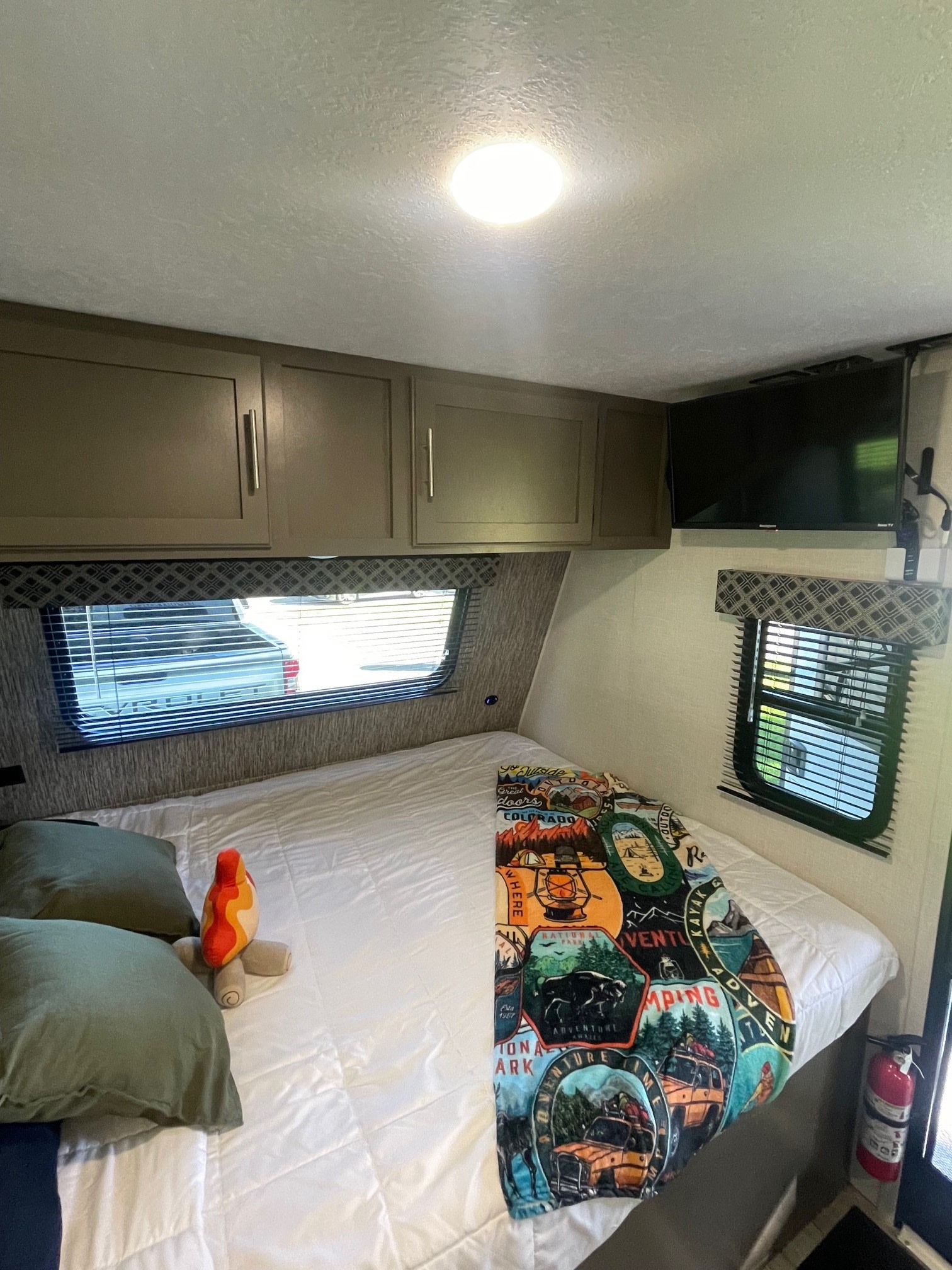 RV rental bedroom: a cozy space with a bed, adventure-themed blanket, overhead cabinets, and windows for camping travel.. KZ SPORTSMEN CLASSIC 191BHK 2024