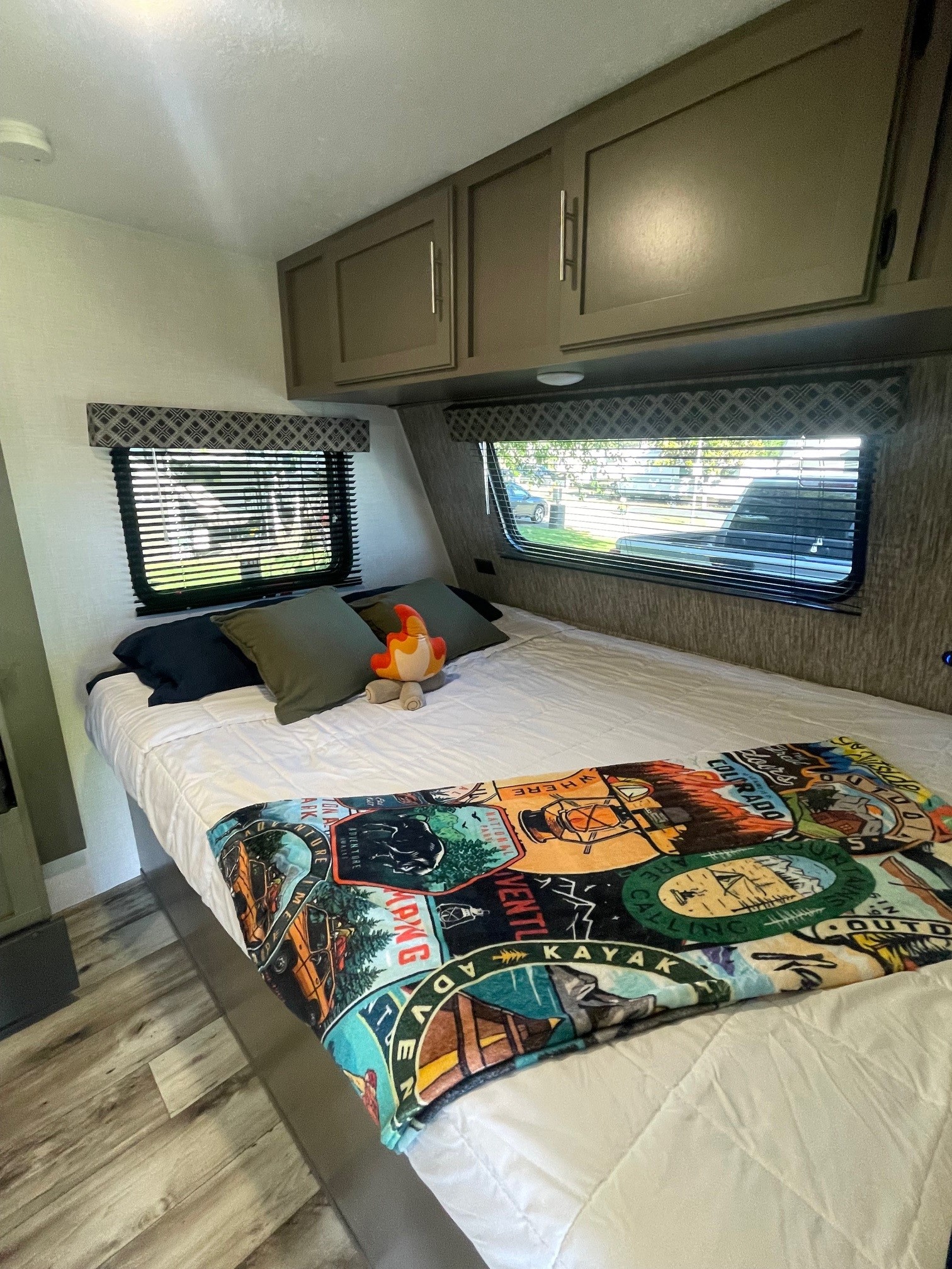 Cozy RV rental bedroom with a comfortable bed, vibrant adventure blanket, and window views. Ideal for your next trip!. KZ SPORTSMEN CLASSIC 191BHK 2024