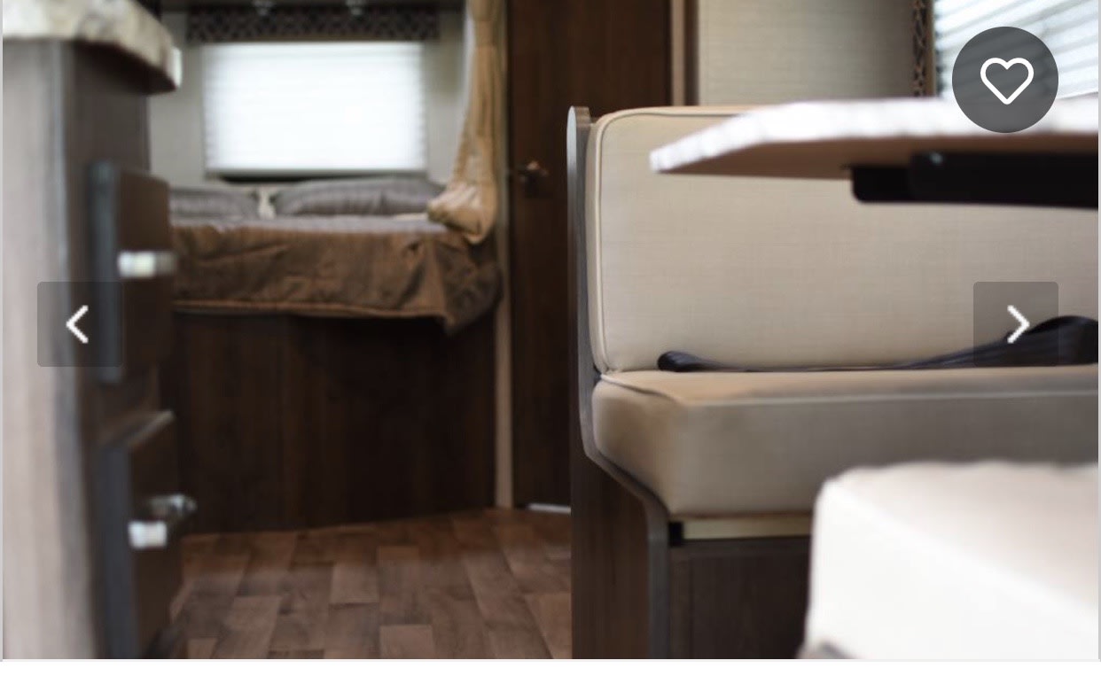 Inside an RV rental, showing a cozy dinette, comfortable bed area, and wood-look flooring. Ready for your travels!. Jayco Redhawk 2019