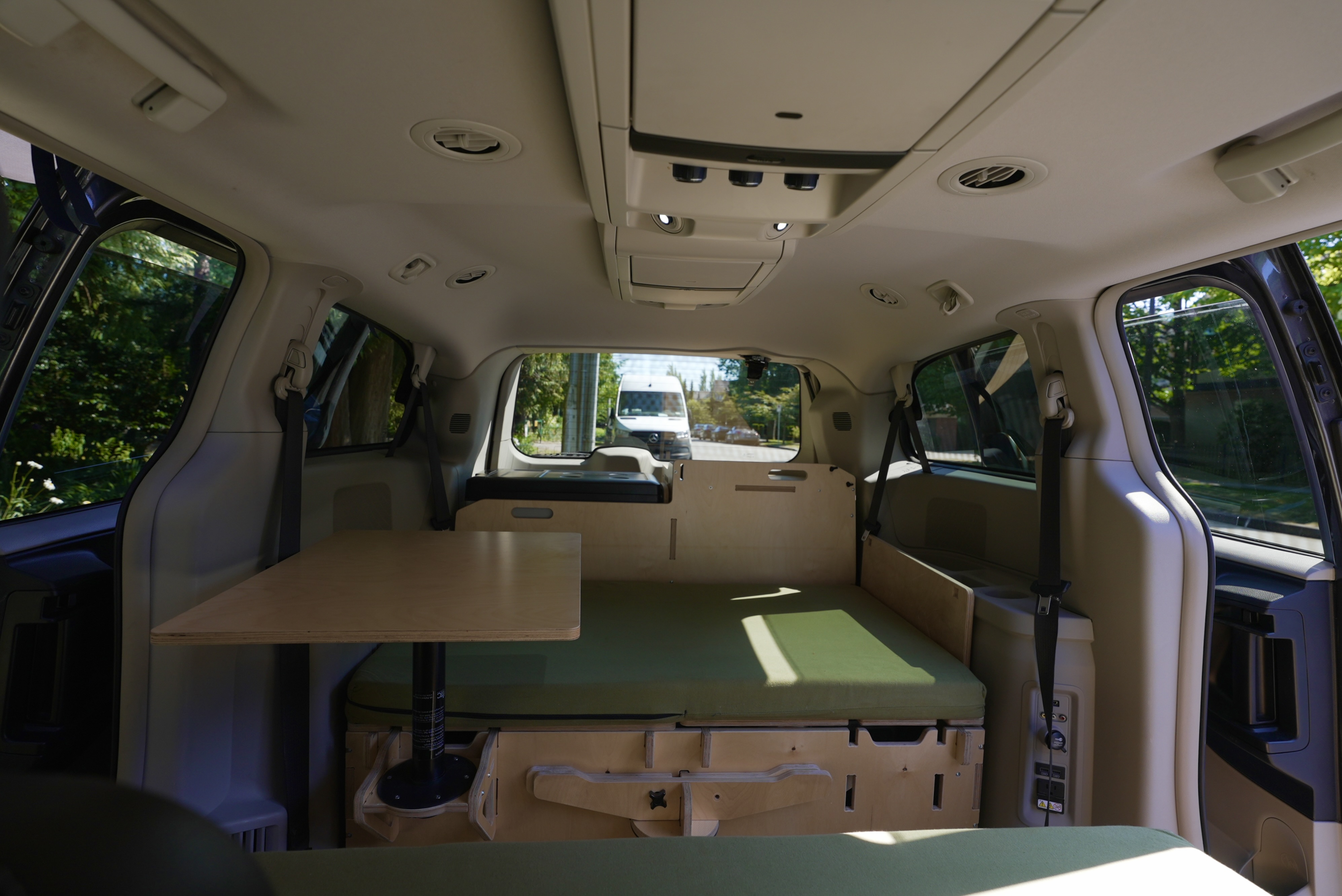 Inside a compact **RV rental**, showing a clever modular bed, table, and storage system for easy travel.. Dodge Caravan 2015