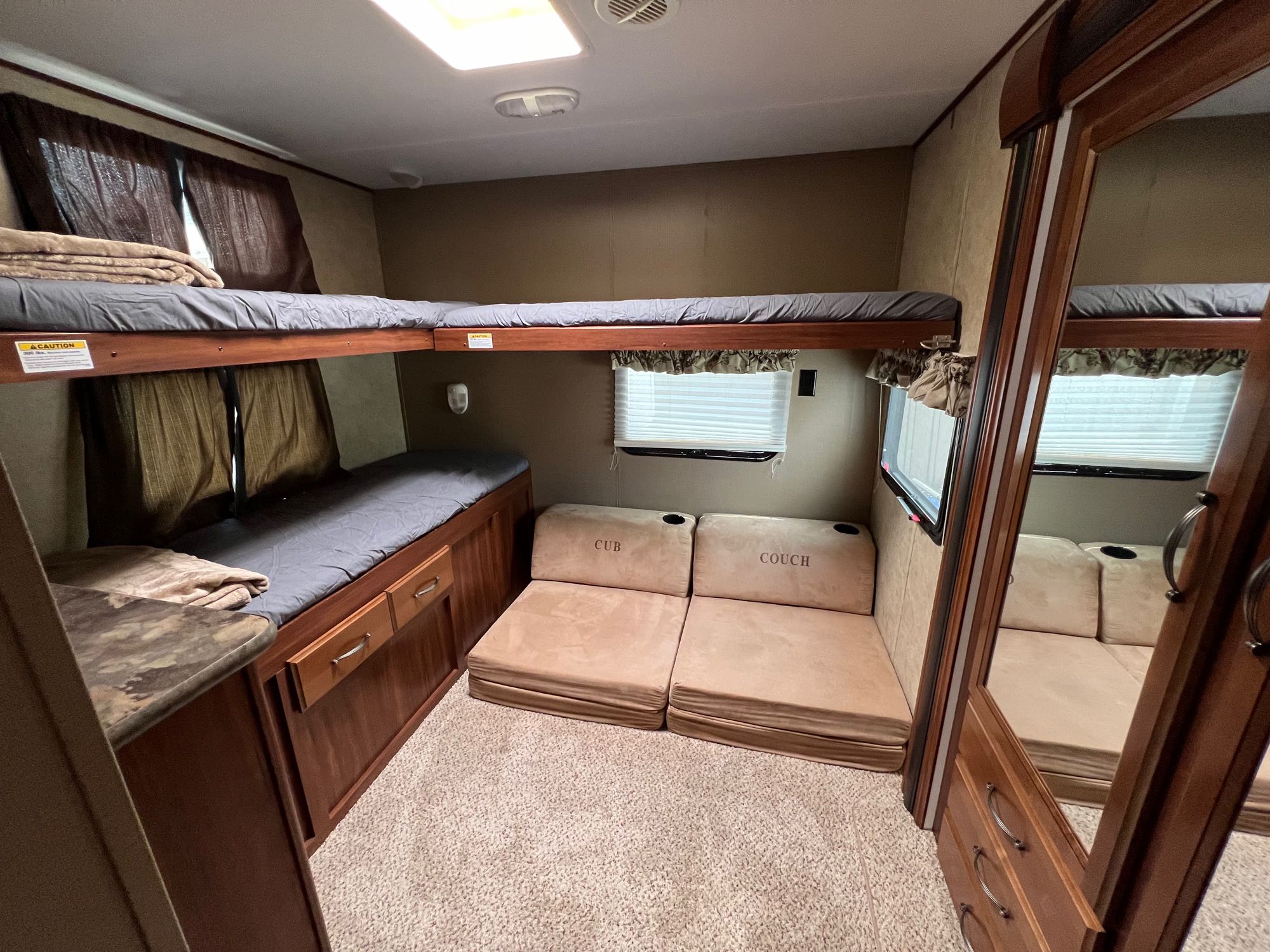 Inside this RV rental, find a compact bunk room with two stacked beds and adaptable seating, perfect for family adventures.. Keystone RV Cougar M-31 SQBWE Half-Ton Series 2015