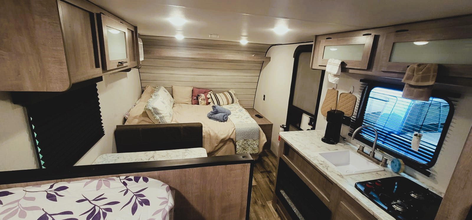 Cozy RV rental interior showcasing a bed, kitchen, and dining area, perfect for comfortable travel.. Coleman 17B 2024
