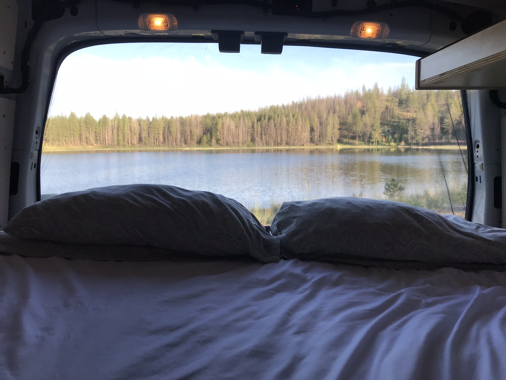 Waking up to a beautiful lake view from a cozy bed in an RV rental. Ideal for nature escapes.. Ford Transit 2015