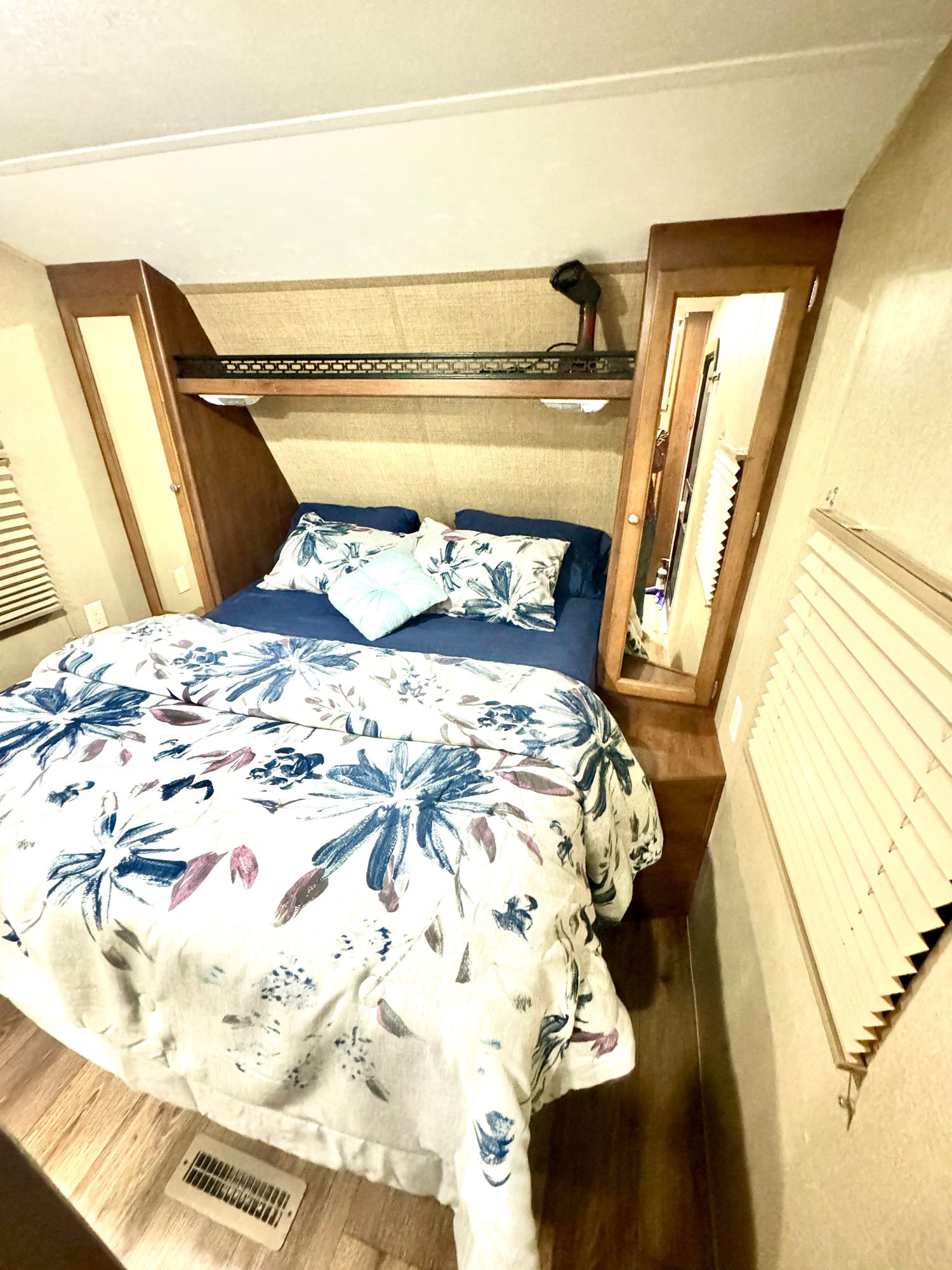 Cozy RV rental bedroom with a floral bedspread, built-in storage, and bright interior lighting.. Aspen Trail Aspen Trail Trailer 2014