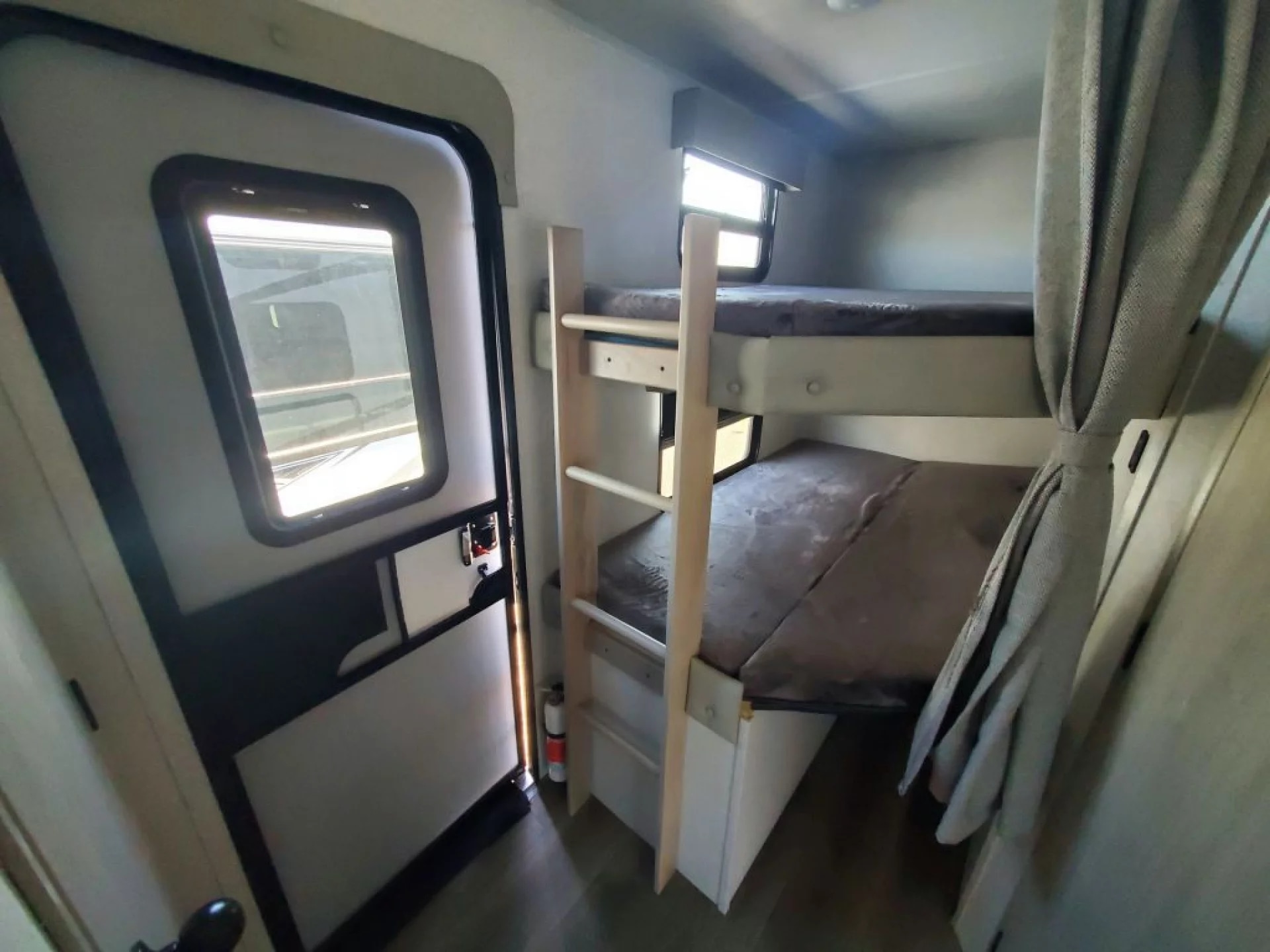 This RV rental's interior features compact bunk beds with a ladder, providing efficient sleeping quarters for your travels.. Forest River East to West 2022