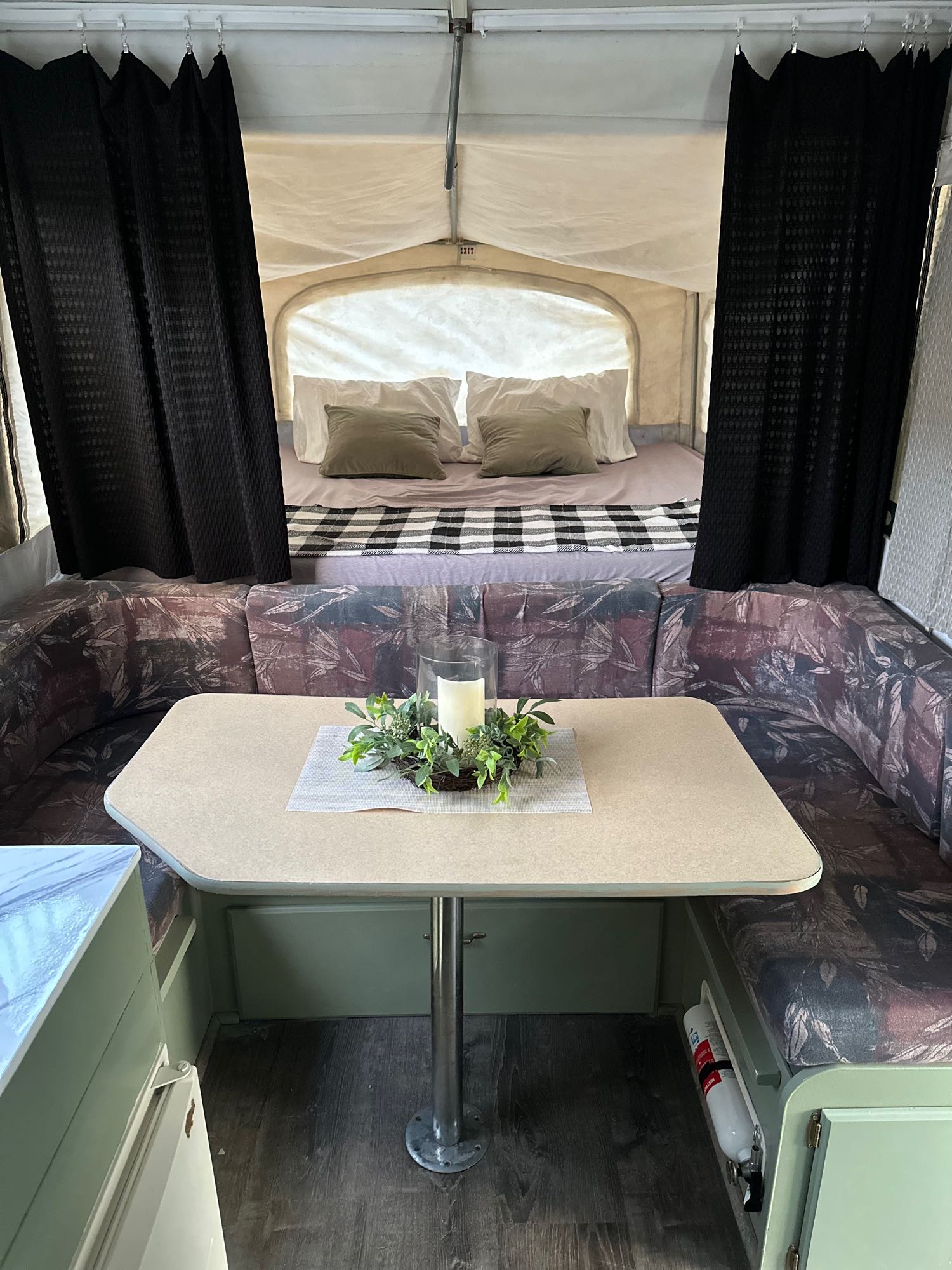 RV rental interior: cozy pop-up camper dinette & bed with black curtains, ideal for compact travel.. Jayco Eagle 2001