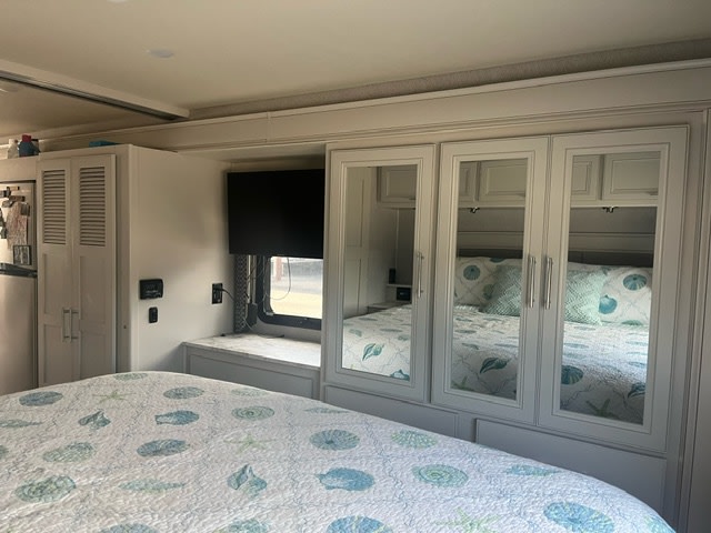 Compact RV rental bedroom offers comfort. Features seashell bedding, mirrored wardrobe, and TV.. Holiday Rambler Admiral 2022