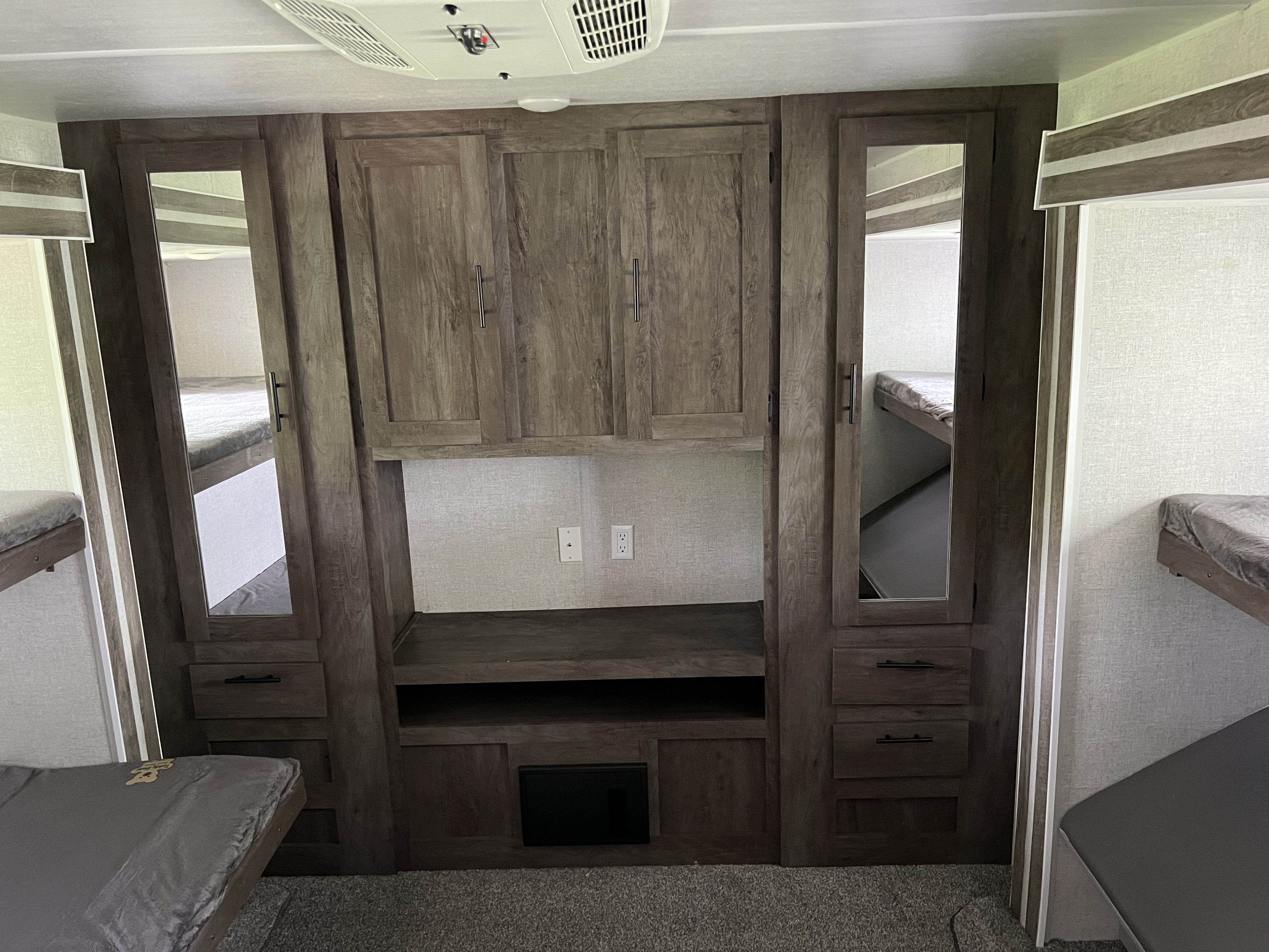 RV rental bunkhouse interior: wood-grained cabinets, mirrored wardrobes, and comfy bunk beds for a cozy stay.. Forest River Salem 2021