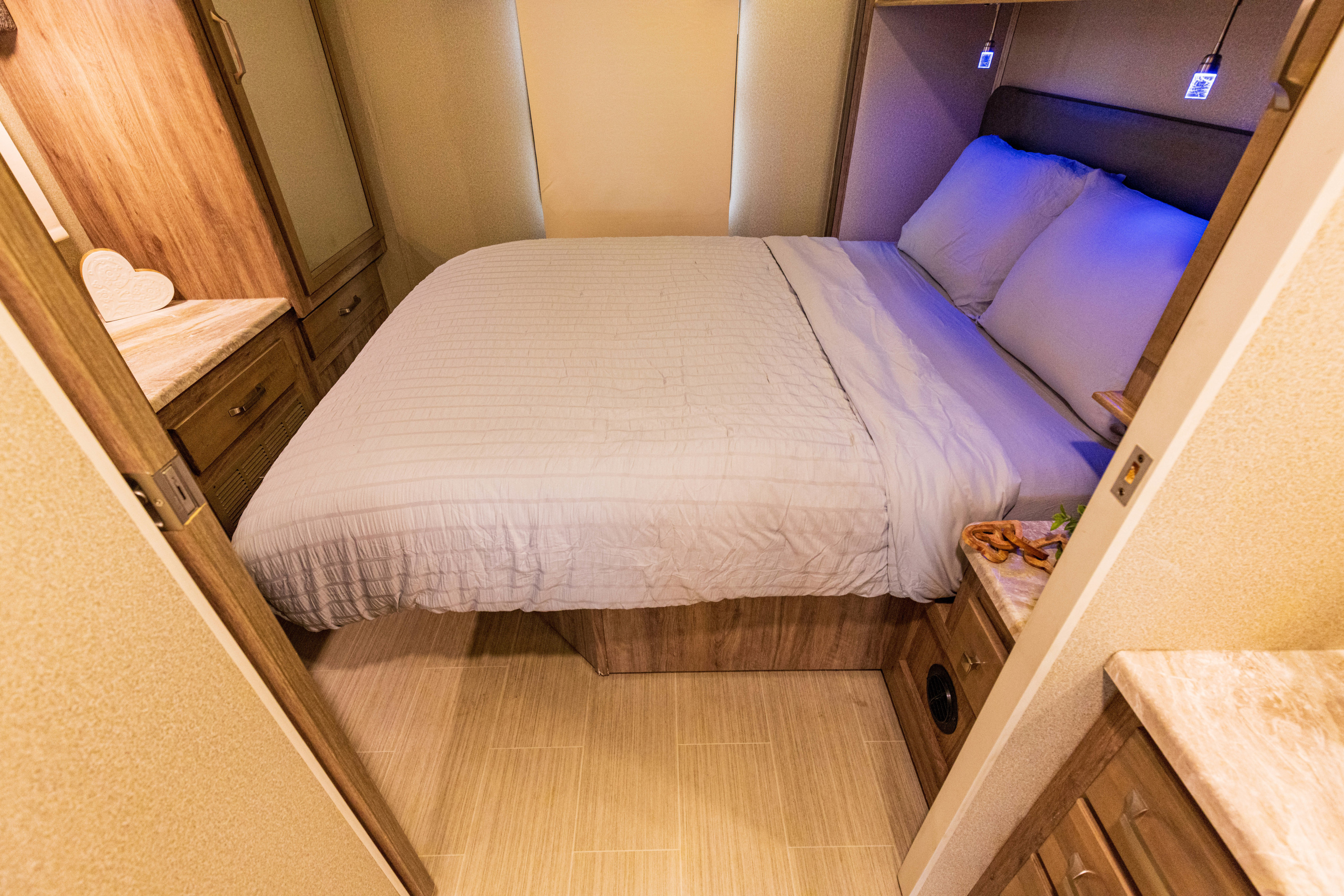 Cozy RV rental bedroom with a comfortable bed, built-in storage, and unique blue accent lighting.. Jayco Greyhawk Prestige 2020