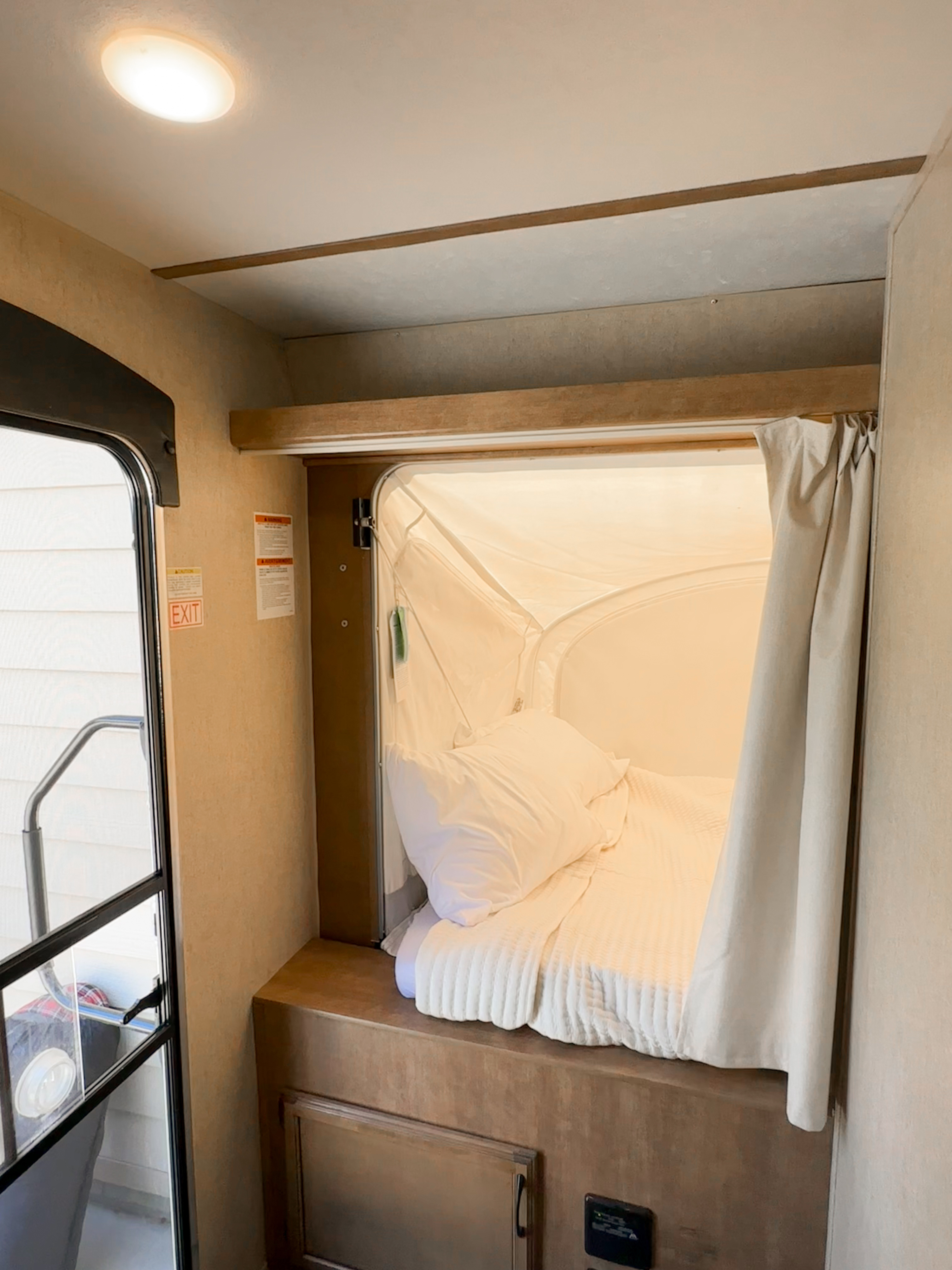 Cozy RV rental interior featuring a bright pop-out bed with white linens and a view of the main entrance.. Starcraft Launch Mini 2018