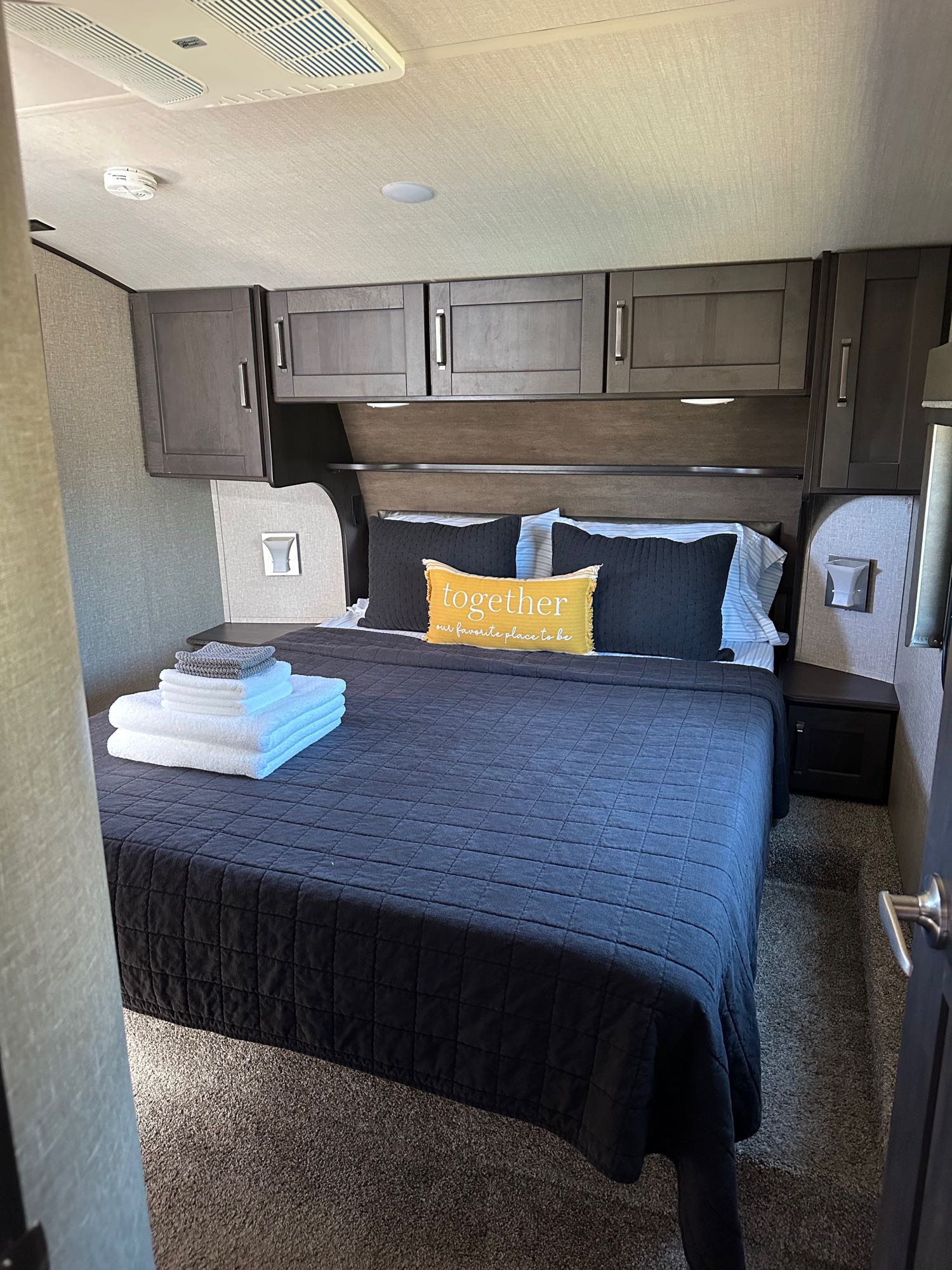 Comfortable RV rental bedroom with a cozy bed, overhead storage, and fresh towels, ready for your adventure.. Grand Design Reflection 2021