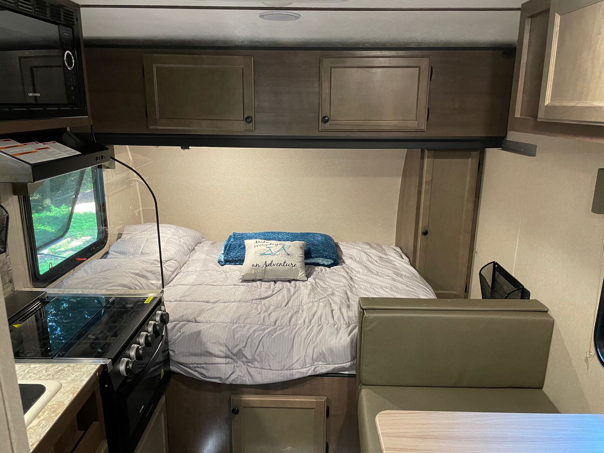 Inside an rv rental: a compact living space featuring a comfortable bed, functional kitchen, and dining area.. Sunset Park RV Sun Lite 2022