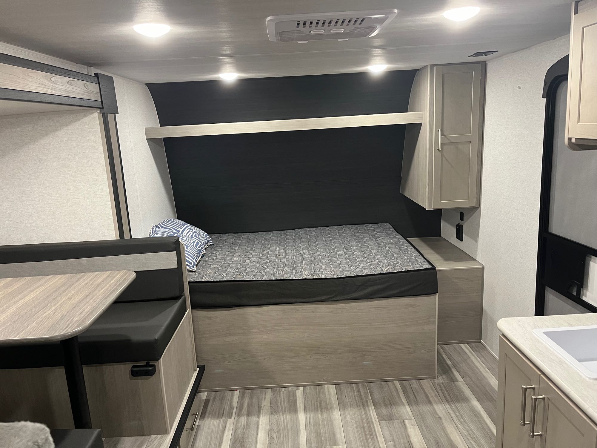 Spacious RV rental interior showcasing a cozy bed, dinette, and compact kitchen, with light wood accents.. Keystone RV Springdale 2024