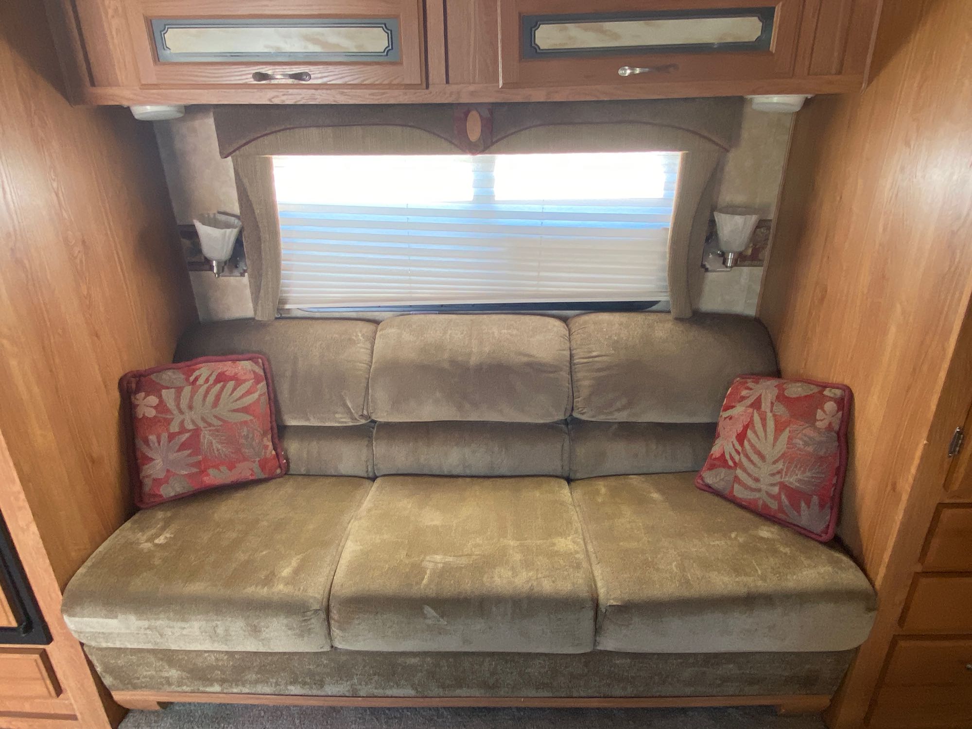 Comfortable RV rental interior featuring a plush sofa with decorative pillows, bright window, and wooden overhead cabinets.. Jayco Jay Flight G2 2008