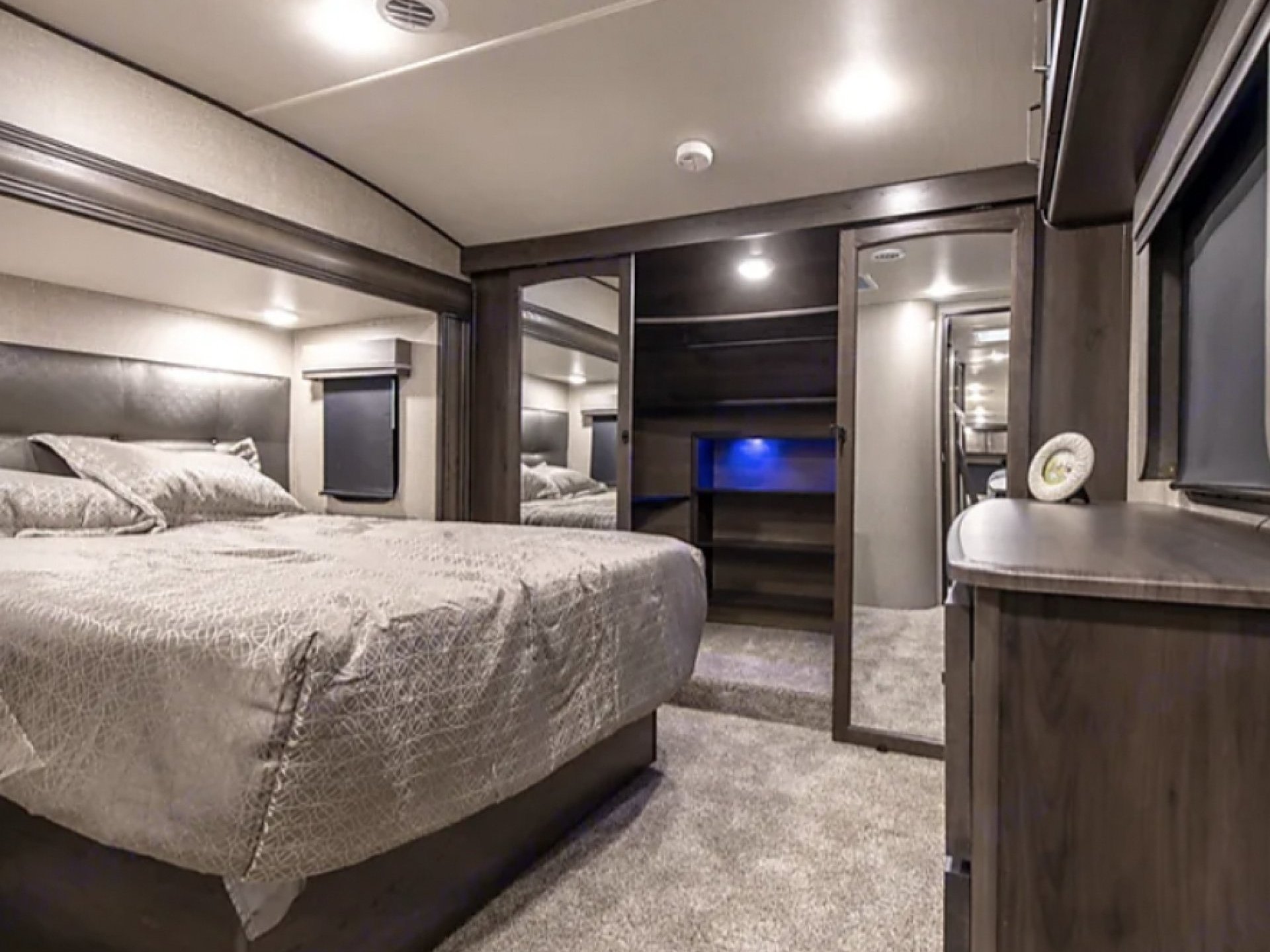 Experience comfort in this well-appointed RV rental bedroom. Features a large bed, storage, and modern interior lighting.. Grand Design Reflection 2023