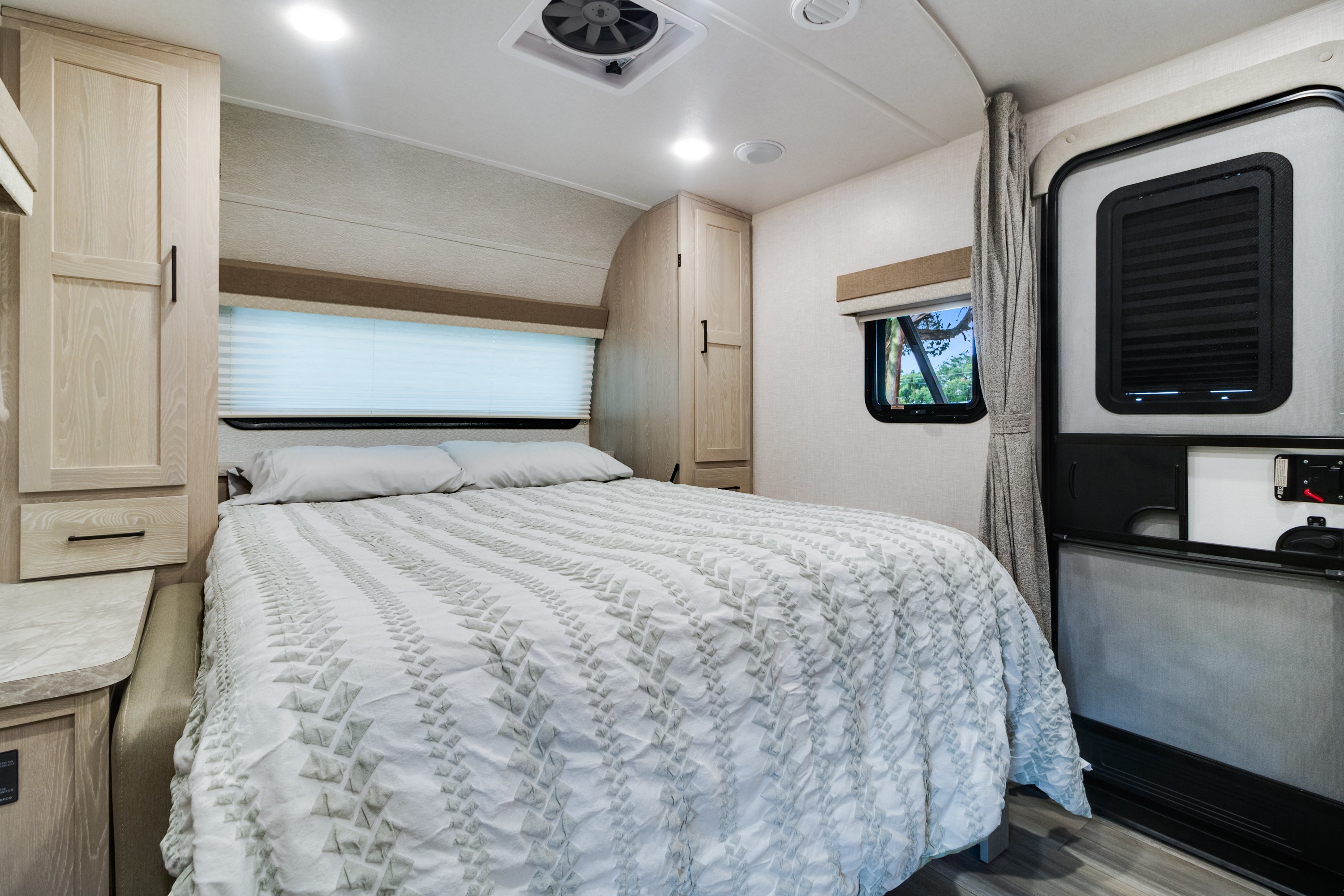 Step into comfort: a cozy RV rental bedroom featuring a full bed, light wood cabinetry, and window with outdoor view.. Forest River Flagstaff Micro Lite 2022