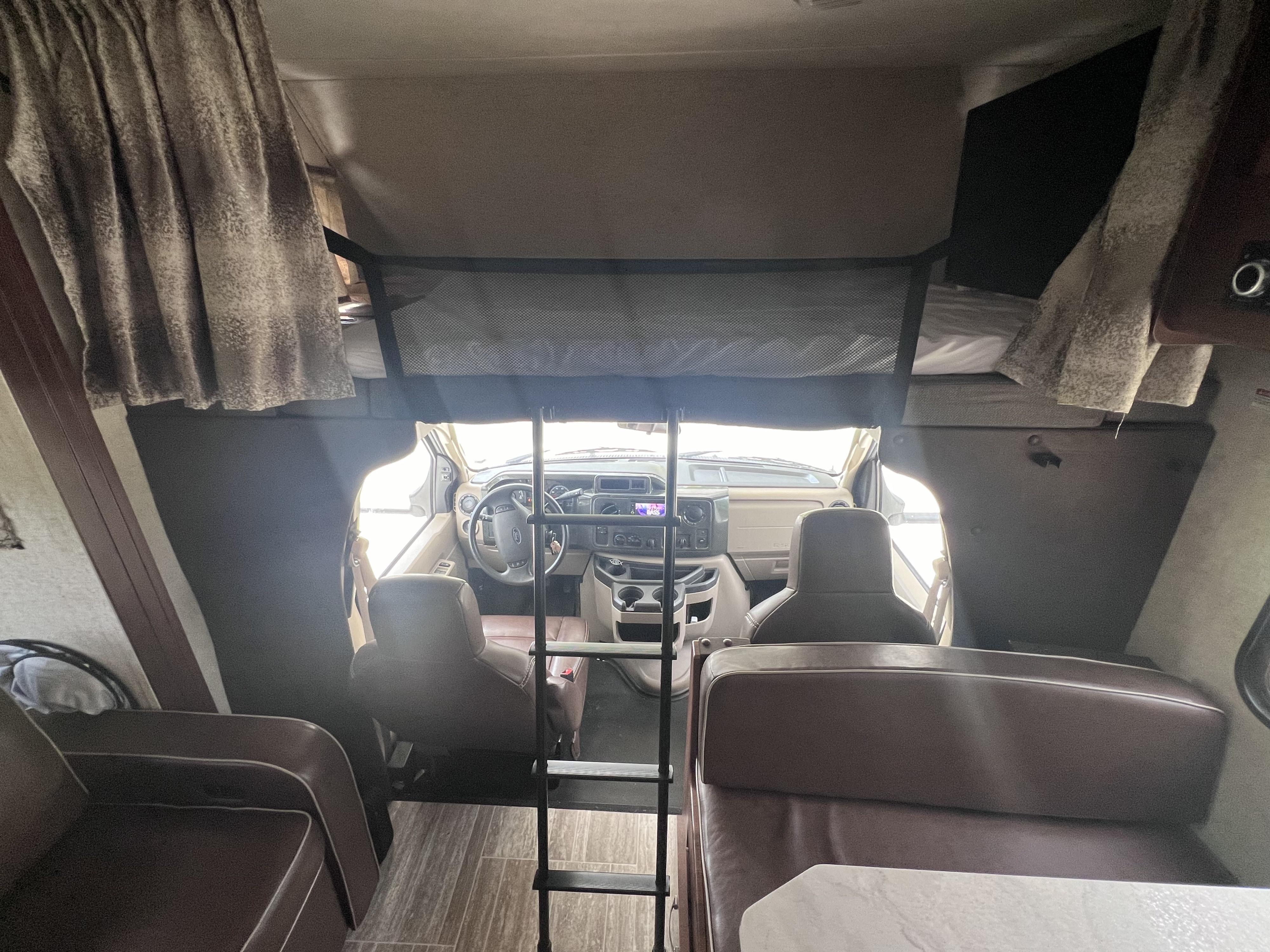 This RV rental interior showcases the driver's cab, a cozy overhead bunk, and a comfortable dining area.. Forest River Forester 2019