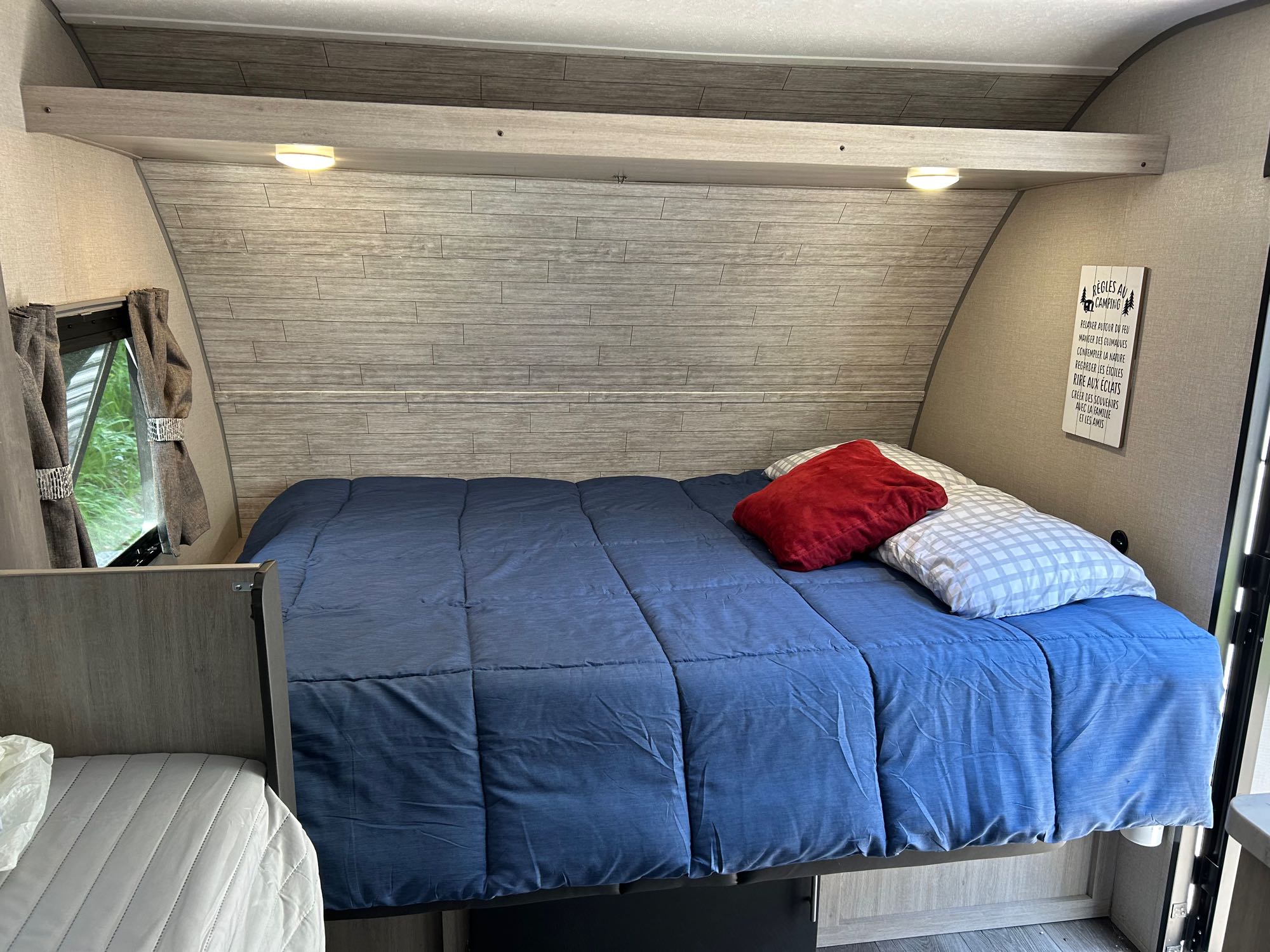 Relax in this cozy RV rental bedroom. Features a comfortable bed, wood paneling, and an inspiring "Camping Rules" sign.. Coachmen Catalina 2024