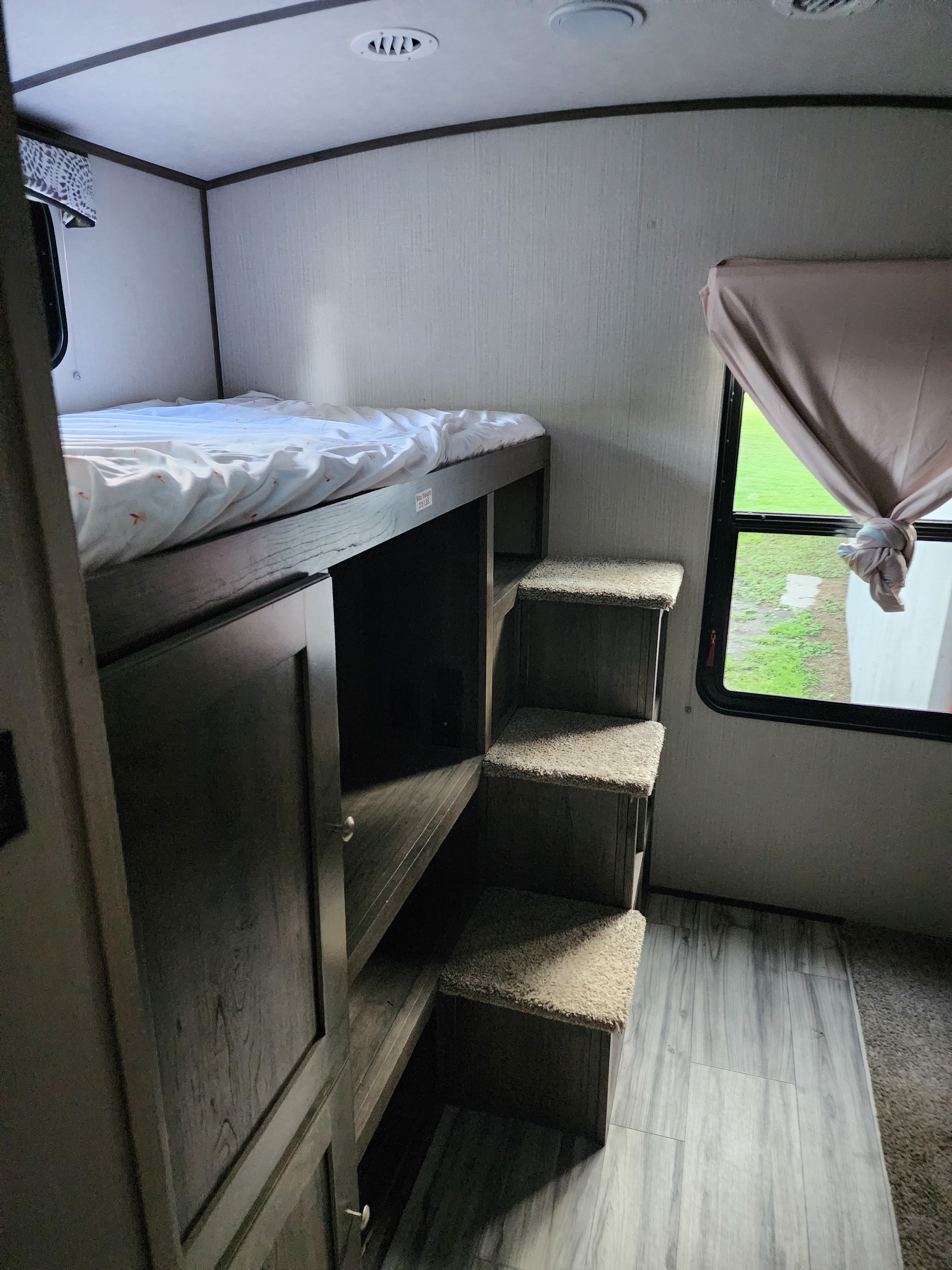 RV rental: interior with a top bunk bed, integrated storage, carpeted steps, and a window view of green outdoors.. Cruiser RV MPG Ultra Lite 2020