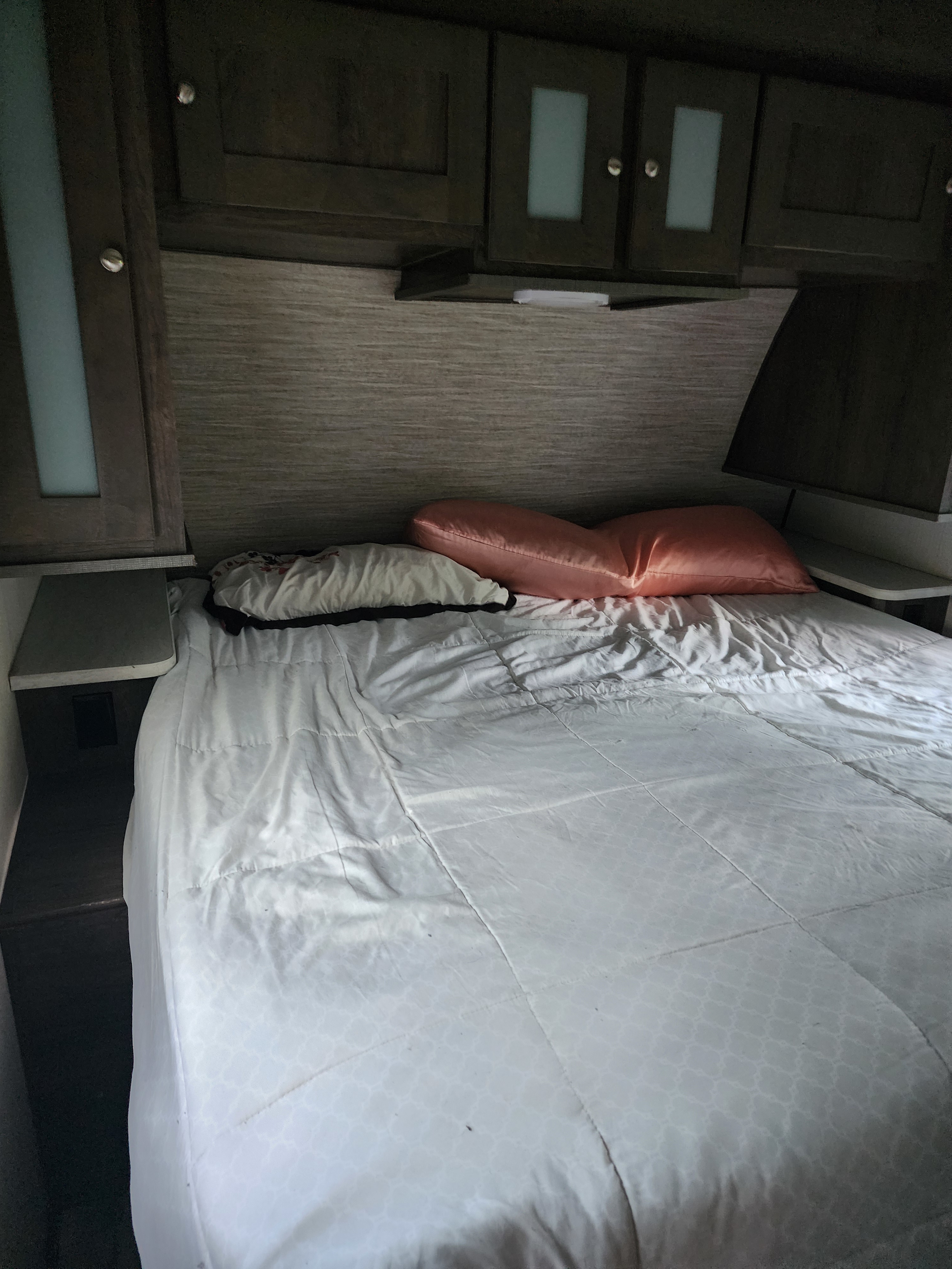 RV rental bedroom: a comfortable bed with pillows and white comforter, dark overhead cabinets, and side shelves.. Cruiser RV MPG Ultra Lite 2020