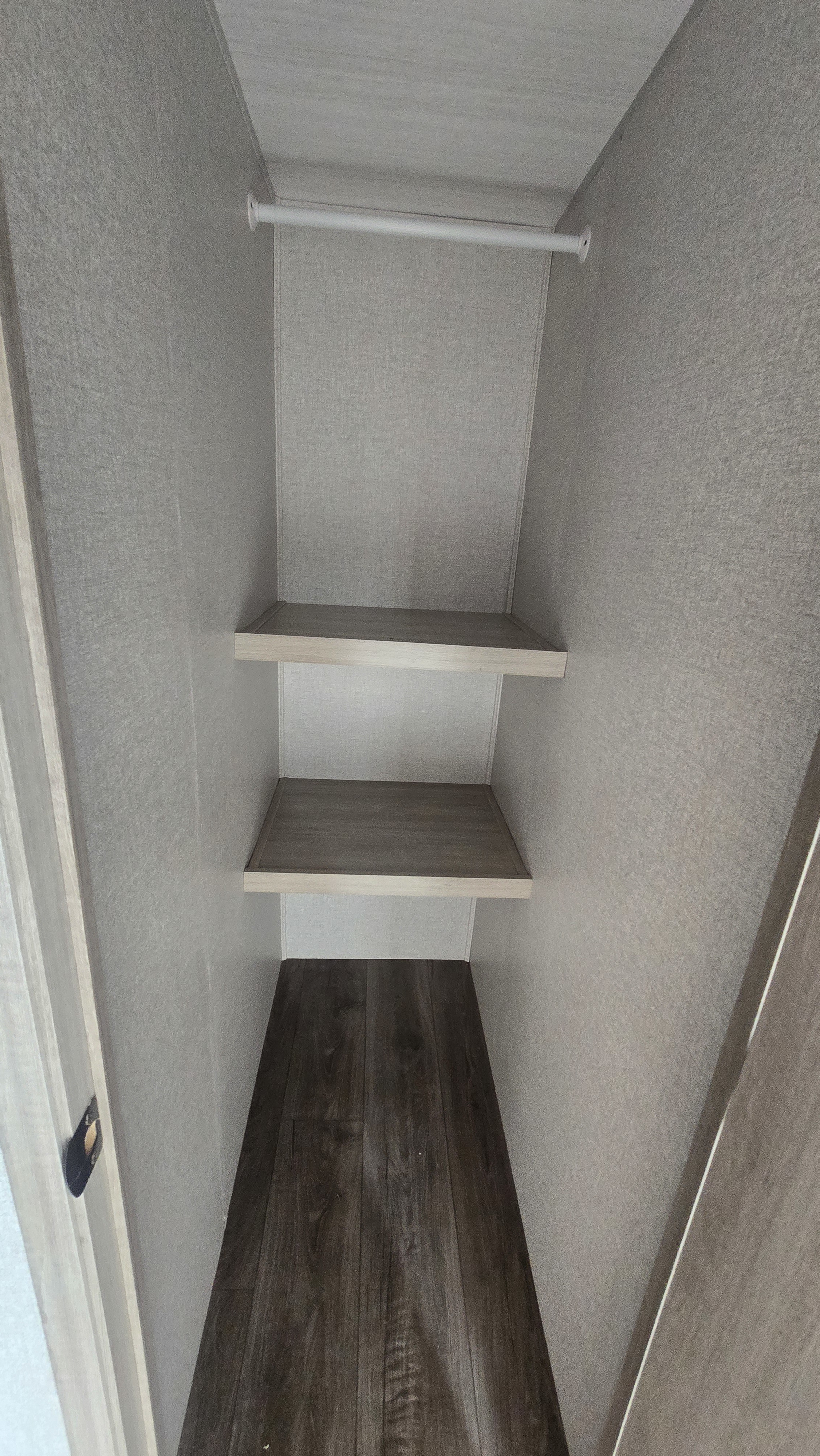 Empty RV rental closet with two shelves, a hanging rod, and wood-look floor for storage.. East to West Alta 2022