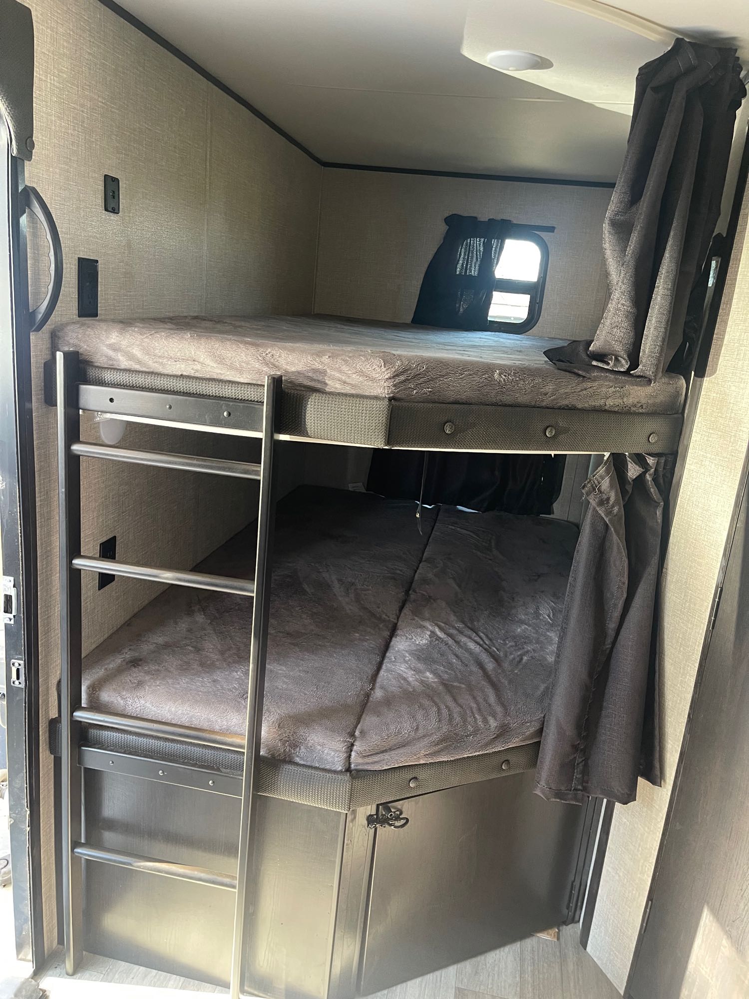 Inside an RV rental, showing a cozy bunk bed setup with a ladder, window, and privacy curtains.. Jayco Jay Flight 2022