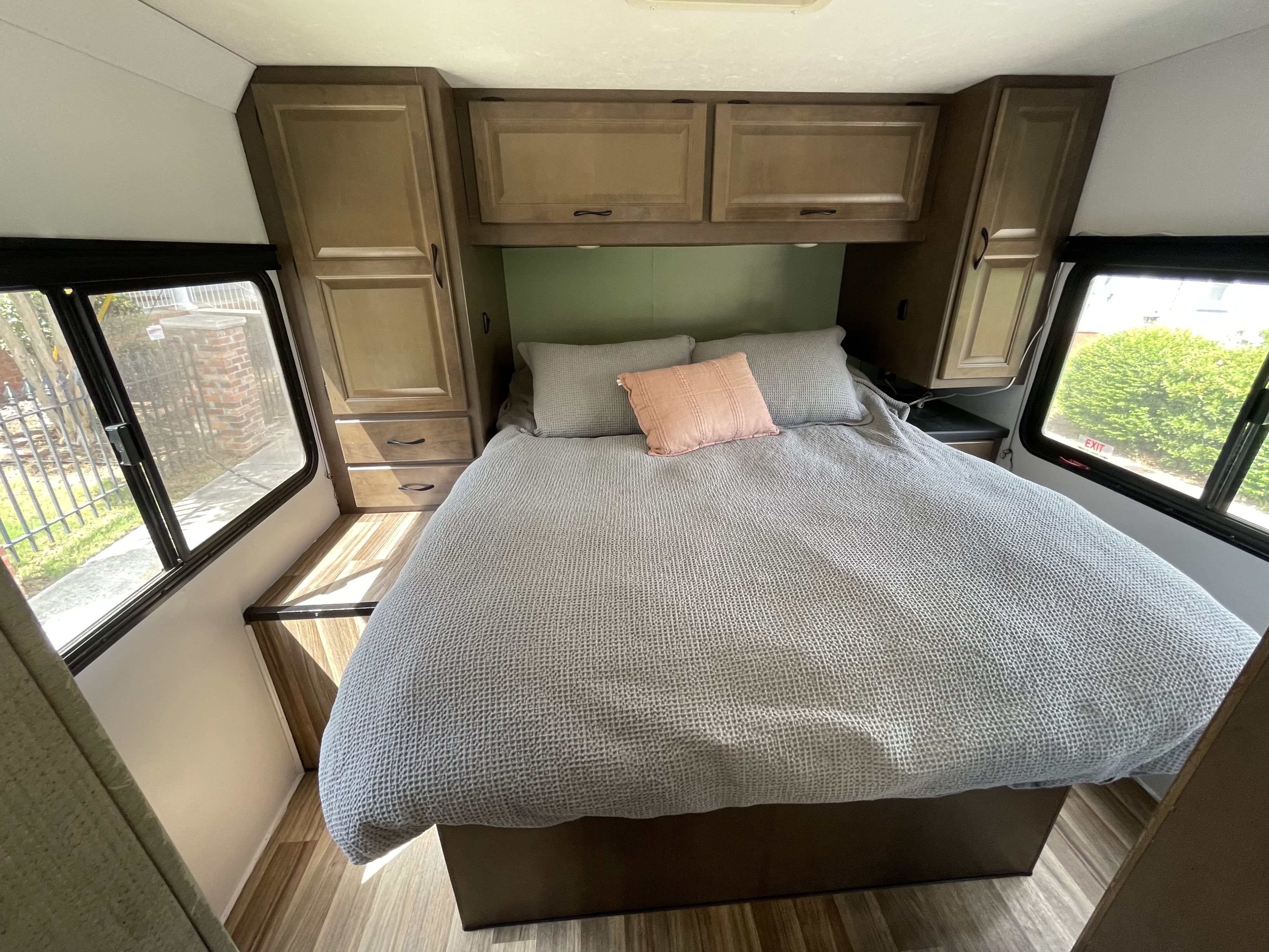 Comfortable RV rental bedroom featuring a cozy bed, overhead storage, and natural light from side windows.. Thor Majestic 2019