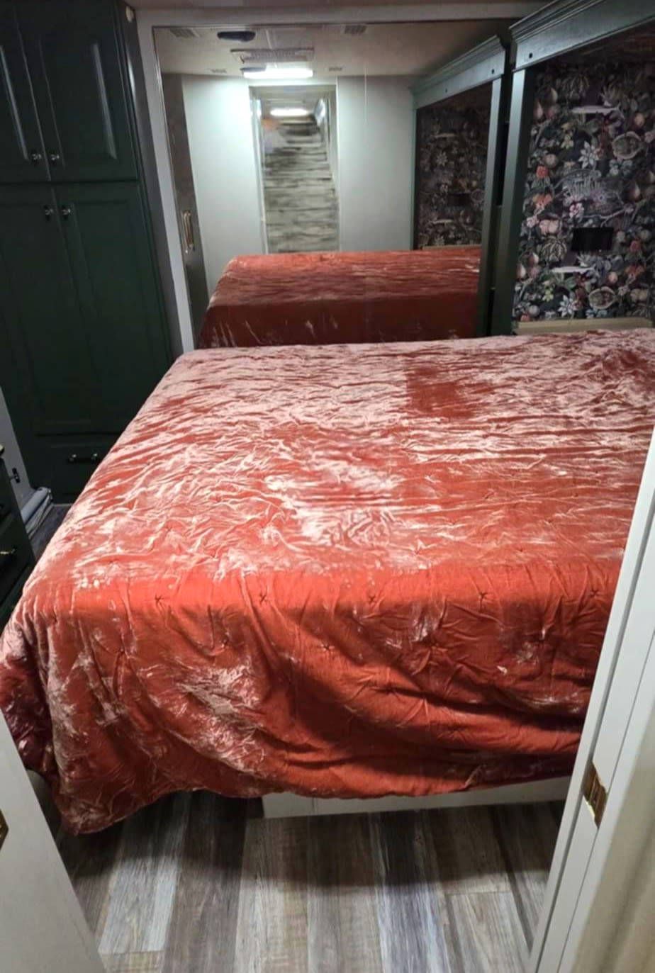 RV rental bedroom with two velvet-covered beds, dark green cabinets, and a large mirror expanding the space.. Country Coach Allure 2004