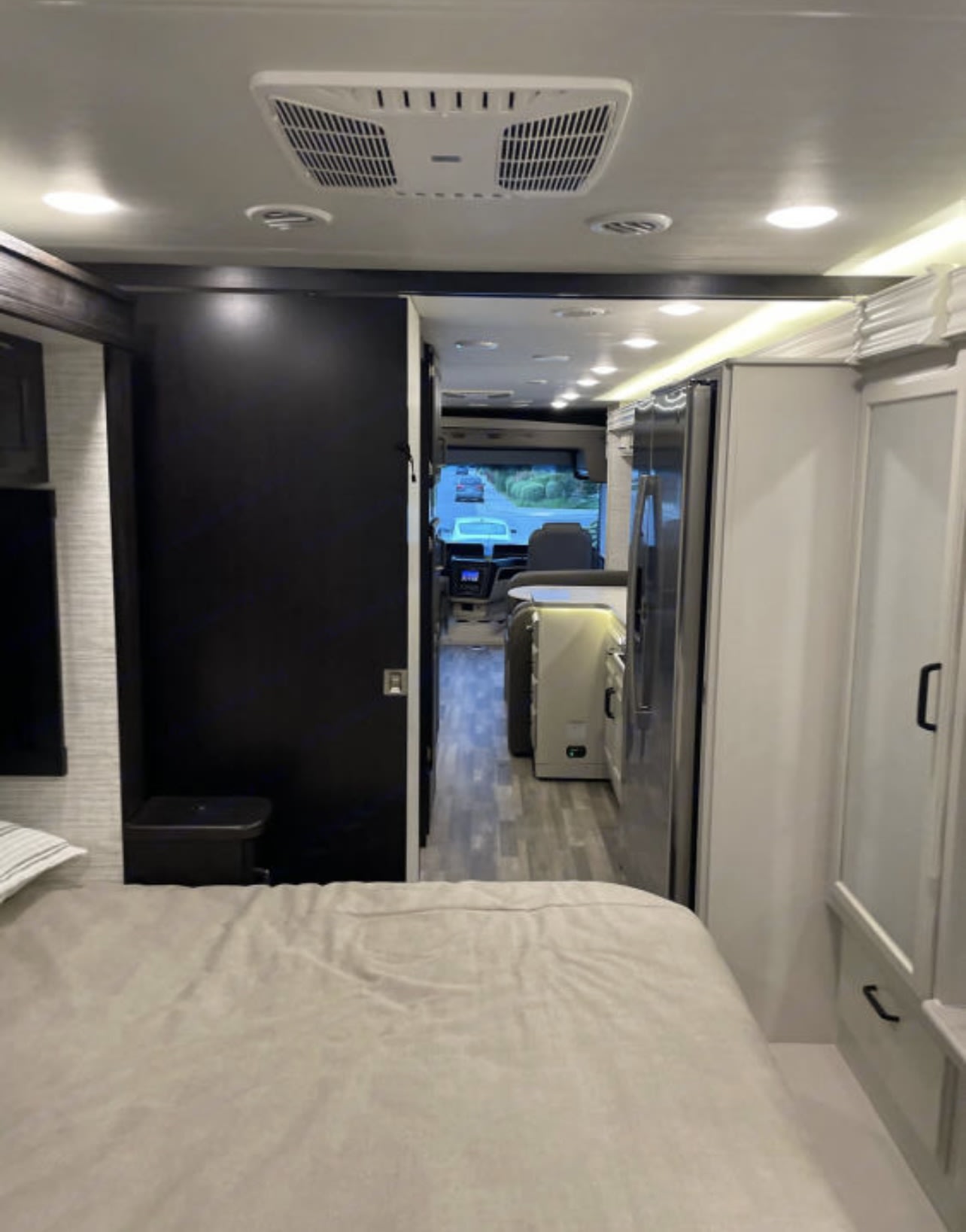 View from the RV rental bedroom, looking down the hallway past the kitchen area towards the front cockpit. Features a modern interior.. Entegra Coach Other 2024