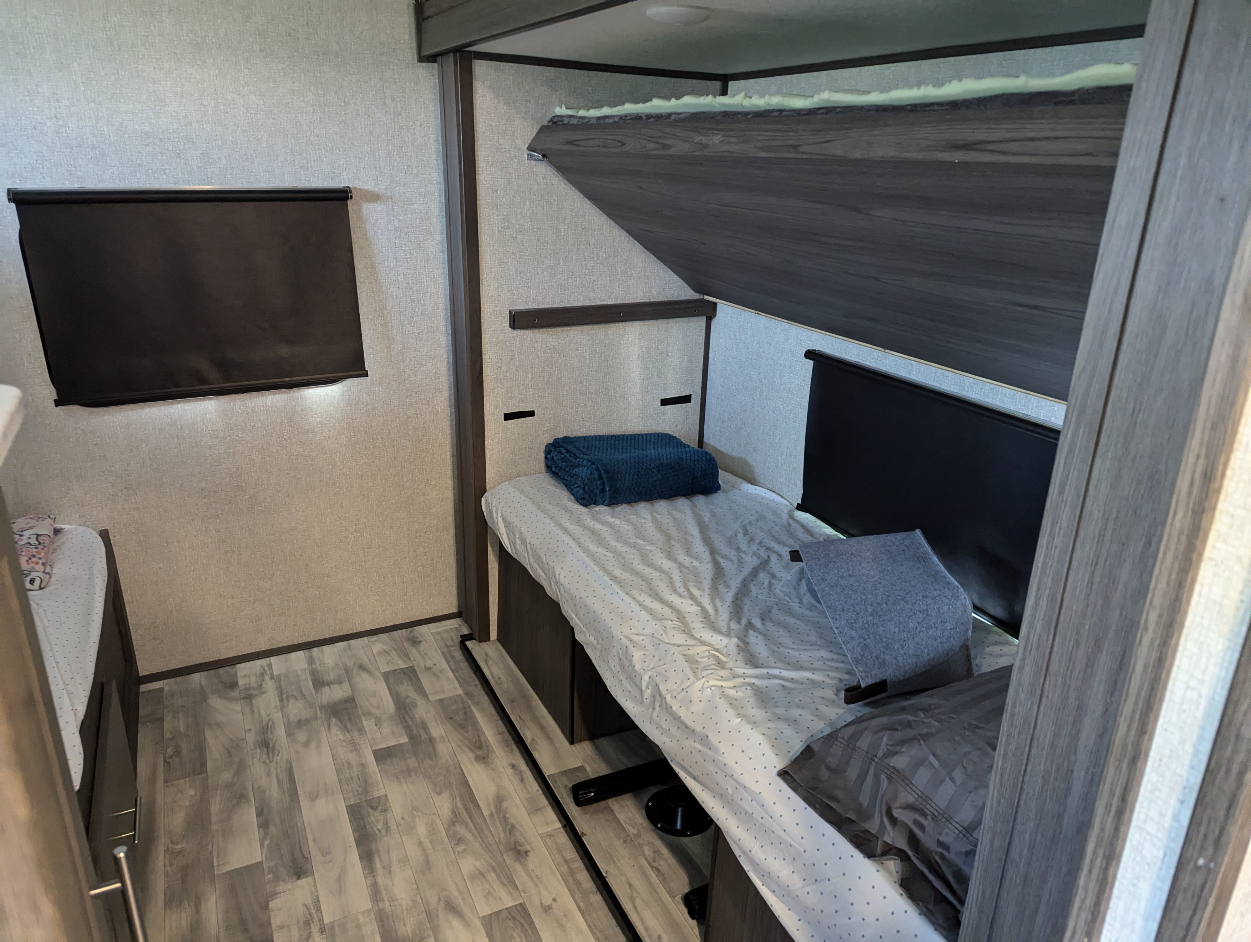 Compact RV rental bedroom with bunk beds, an additional bed, wood-look flooring, and blackout blinds.. Dutchmen Kodiak Ultimate 2021