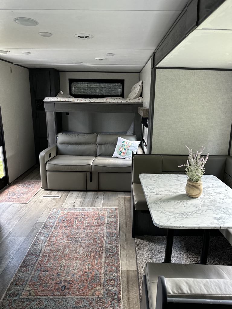 RV rental interior: spacious living area with sofa, bunk beds, and dinette.. Aspen Trail LE 2022