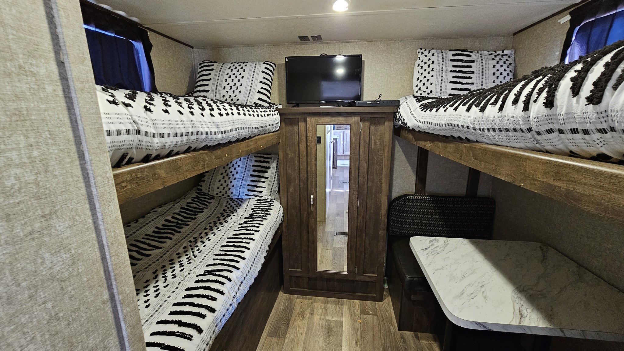 RV rental interior features cozy bunk beds, a central TV cabinet with mirror, and a compact dinette area.. Forest River Vibe Extreme Lite 2017