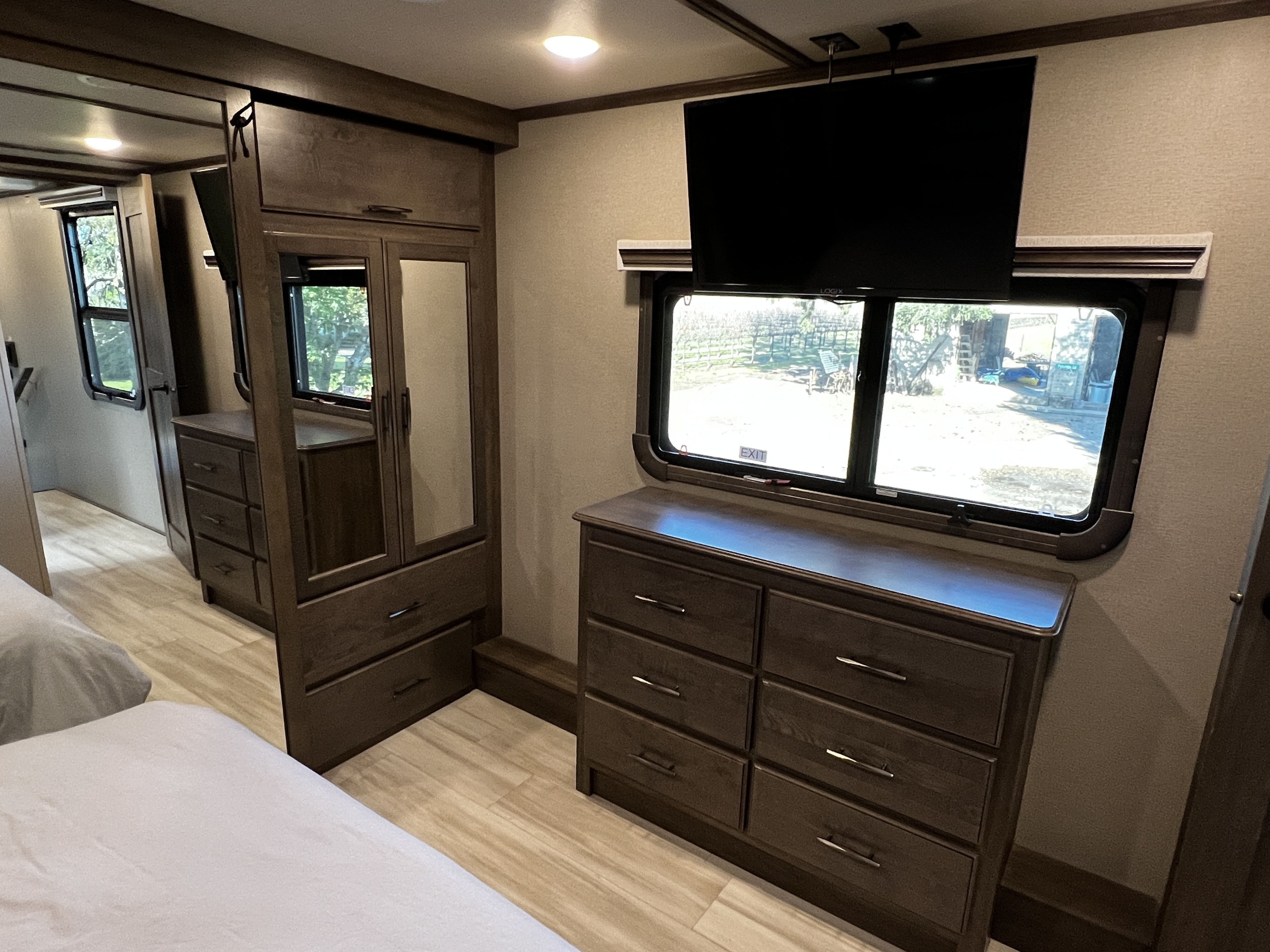 Spacious RV rental bedroom featuring twin beds, built-in dresser, wardrobe, TV, and large windows with outdoor views.. Grand Design Solitude 2022