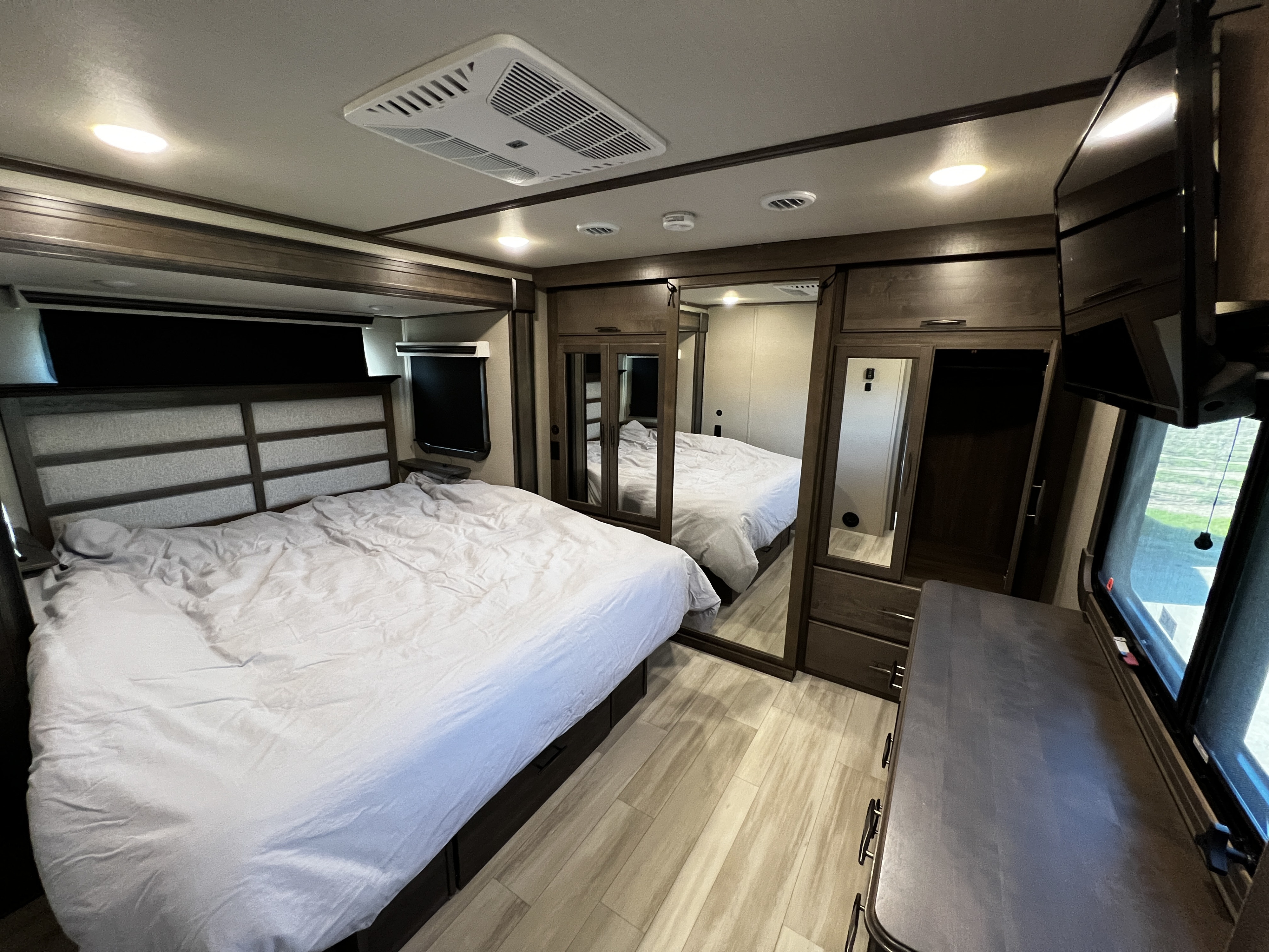 Cozy RV rental bedroom with large bed, ample storage, and modern amenities, perfect for comfortable travel.. Grand Design Solitude 2022