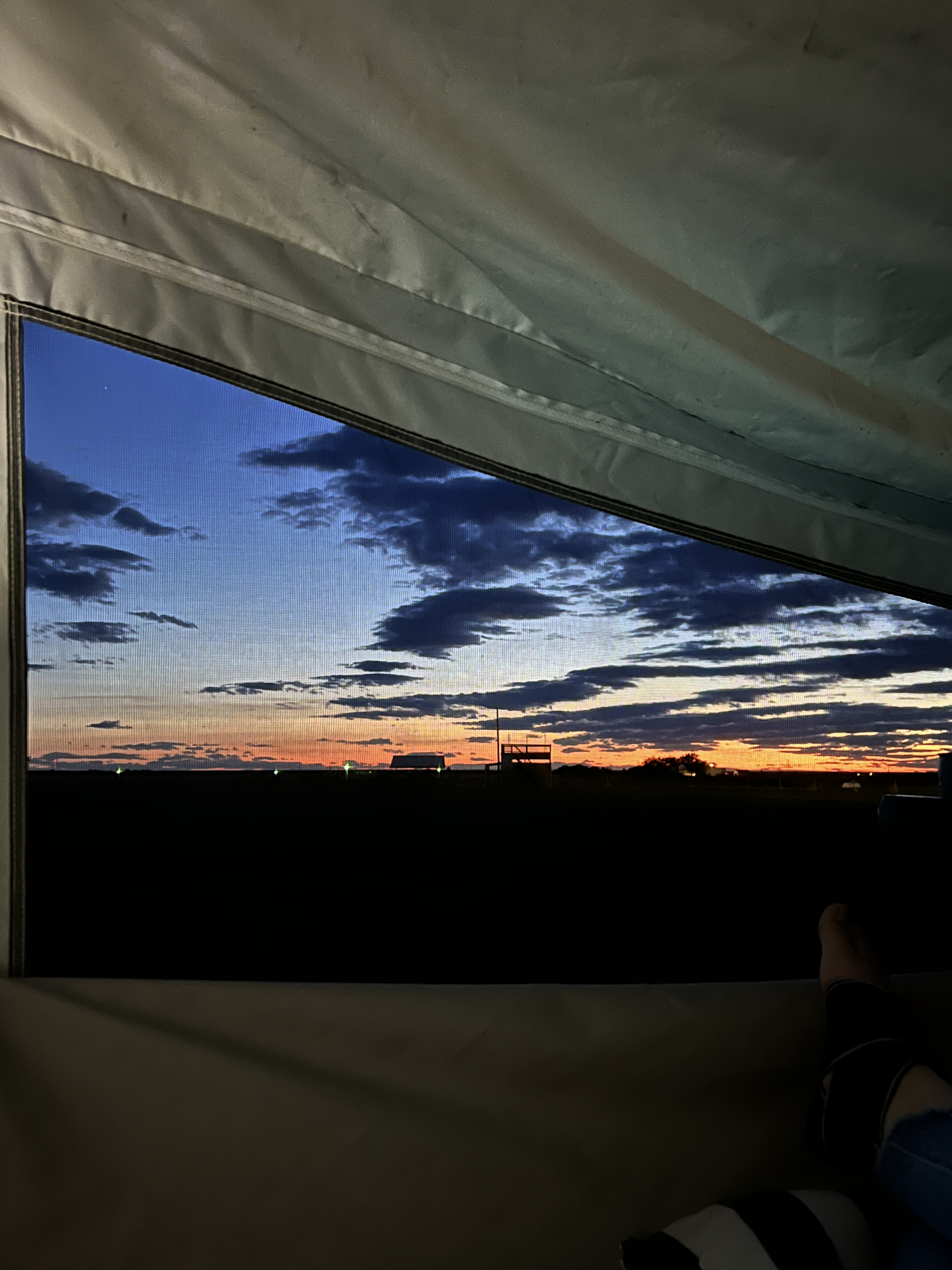 Relaxing inside an RV rental, admiring a stunning sunset through the window screen, showcasing a vibrant sky & distant horizon.. Quicksilver Quicksilver Livin Lite 2011