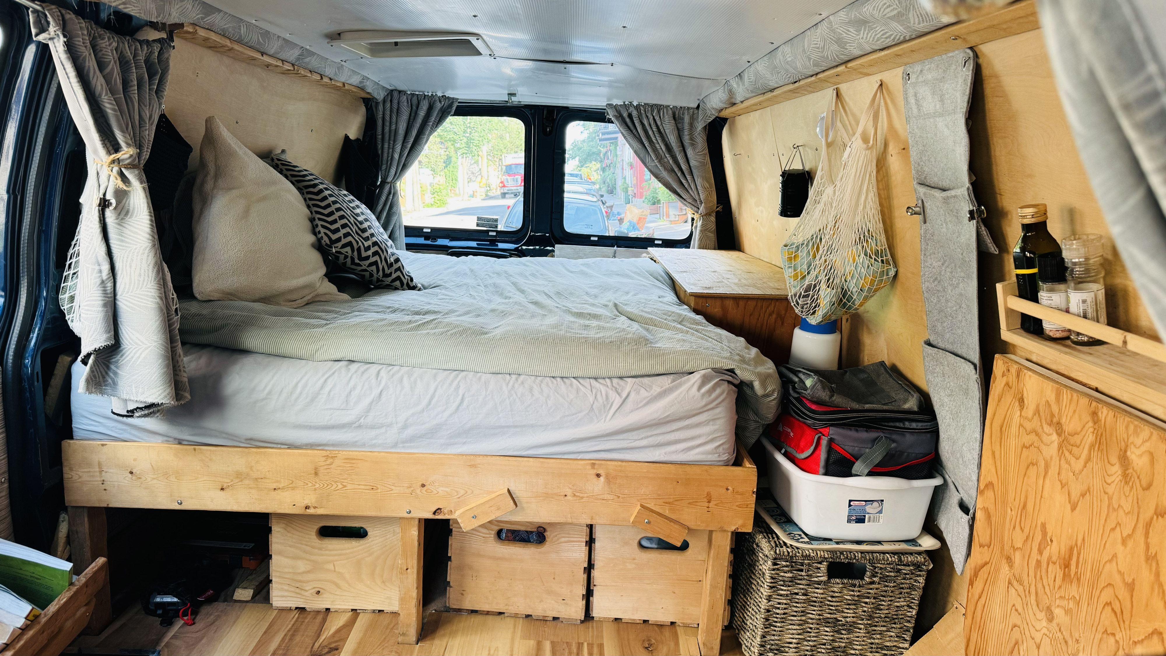Cozy RV rental interior with a comfy bed, curtains, and clever storage solutions. Perfect for road trips.. Chevrolet Express 2001