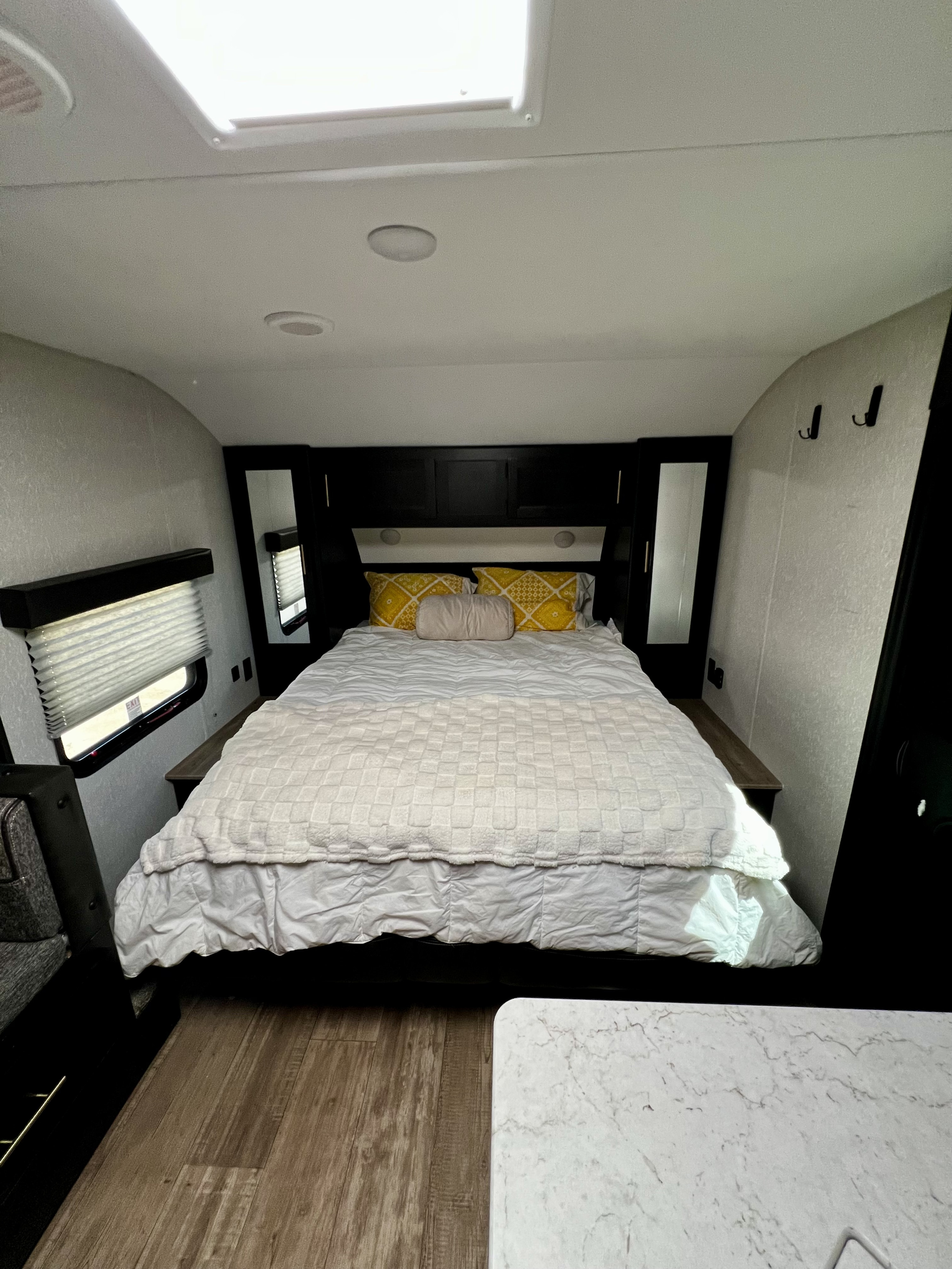 Cozy RV rental bedroom with a queen bed, yellow pillows, built-in storage, and skylight above.. Forest River Cherokee Grey Wolf 2022
