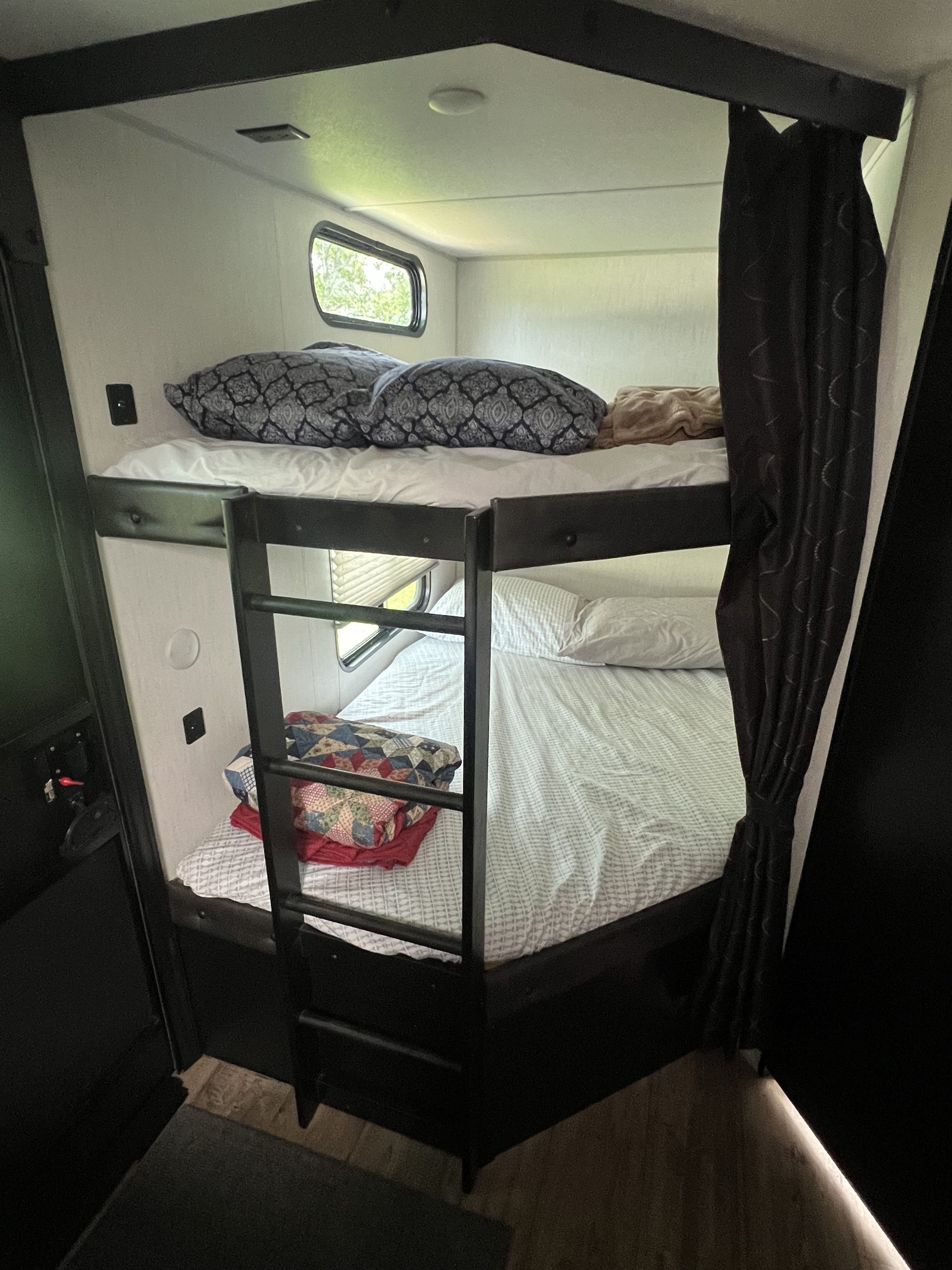 Comfortable bunk beds in an RV rental, offering a cozy sleeping area with windows. Perfect for family adventures.. Forest River Cherokee Grey Wolf 2022