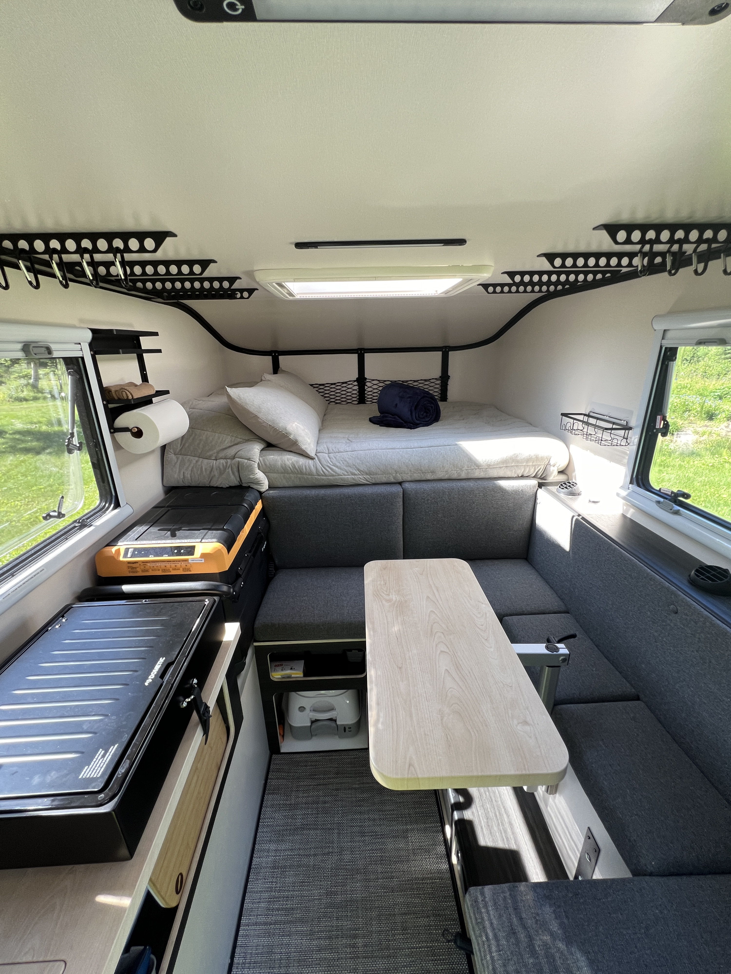 Compact RV rental interior featuring a cozy bed, convertible dining area, and practical kitchenette for travel adventures.. Dodge 1500 2023