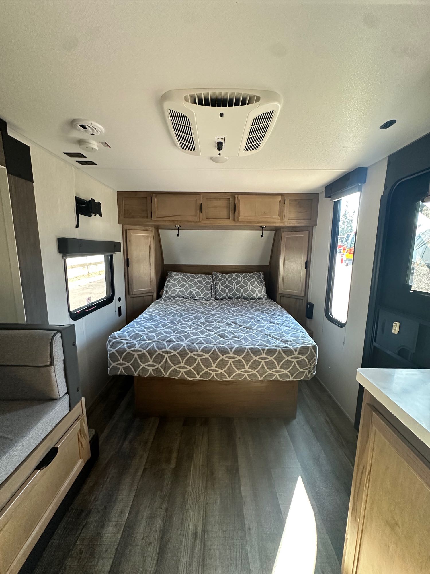 Comfortable RV rental bedroom interior with bed, built-in cabinets, and overhead AC unit. Bright.. Forest River Cherokee Wolf Pup Black Label 2024