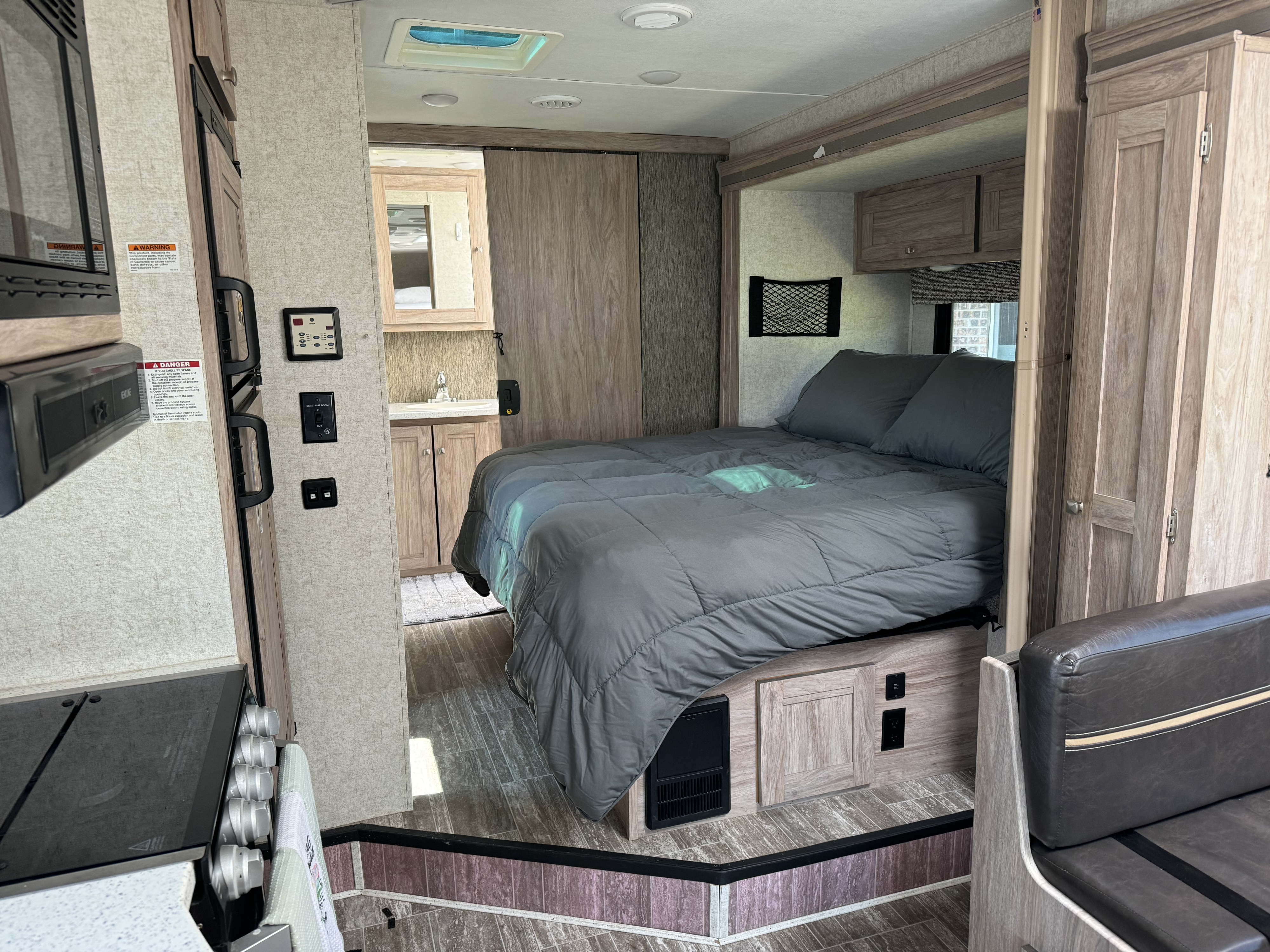 Step inside this RV rental showcasing a cozy bedroom with gray comforter, compact kitchen, and rear bathroom.. Forester Forester Motorhome 2019