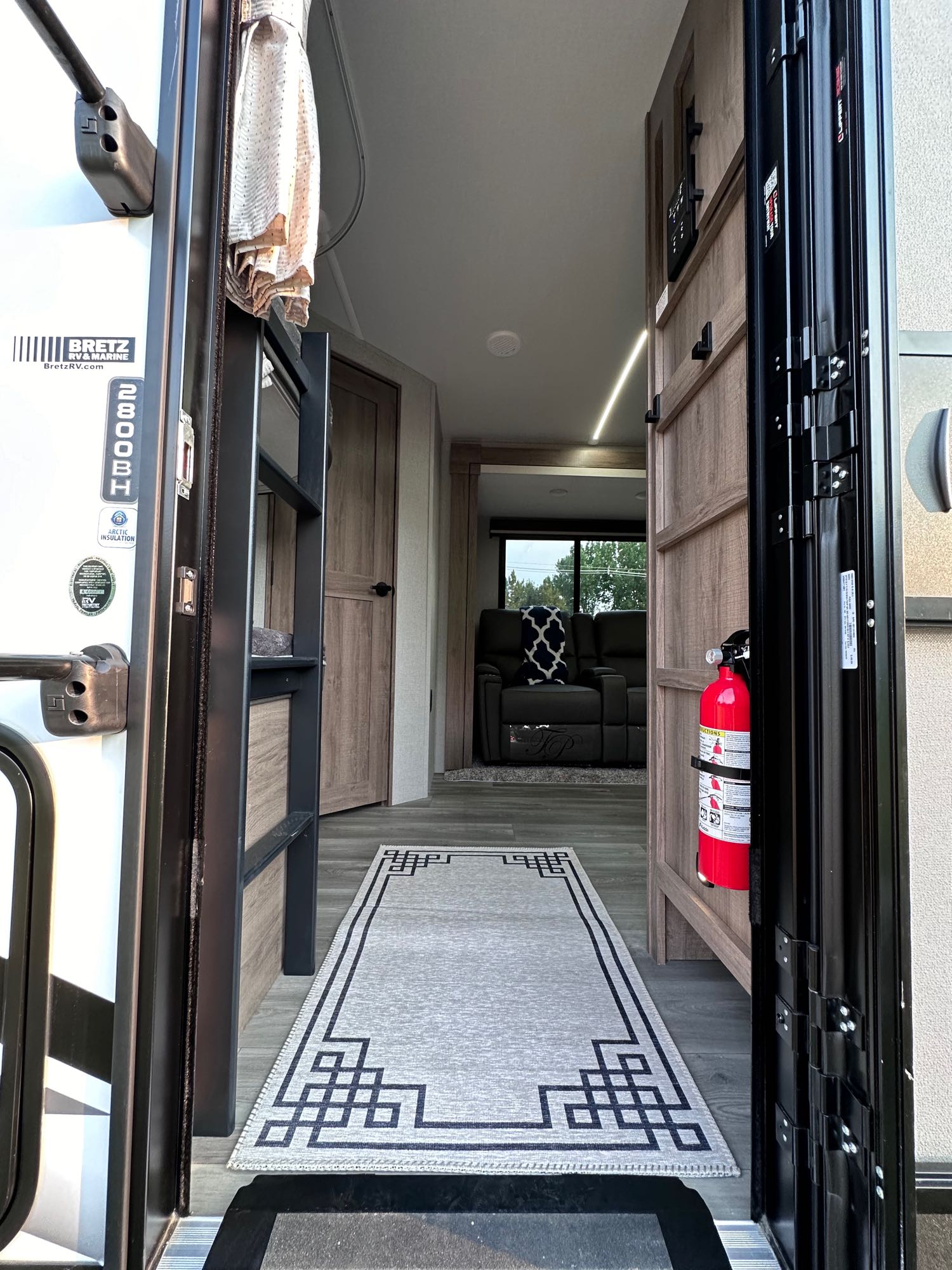 Inside an RV rental: Looking in from the open doorway, showing bunk beds, a fire extinguisher, and comfy living area.. Grand Design Imagine 2024