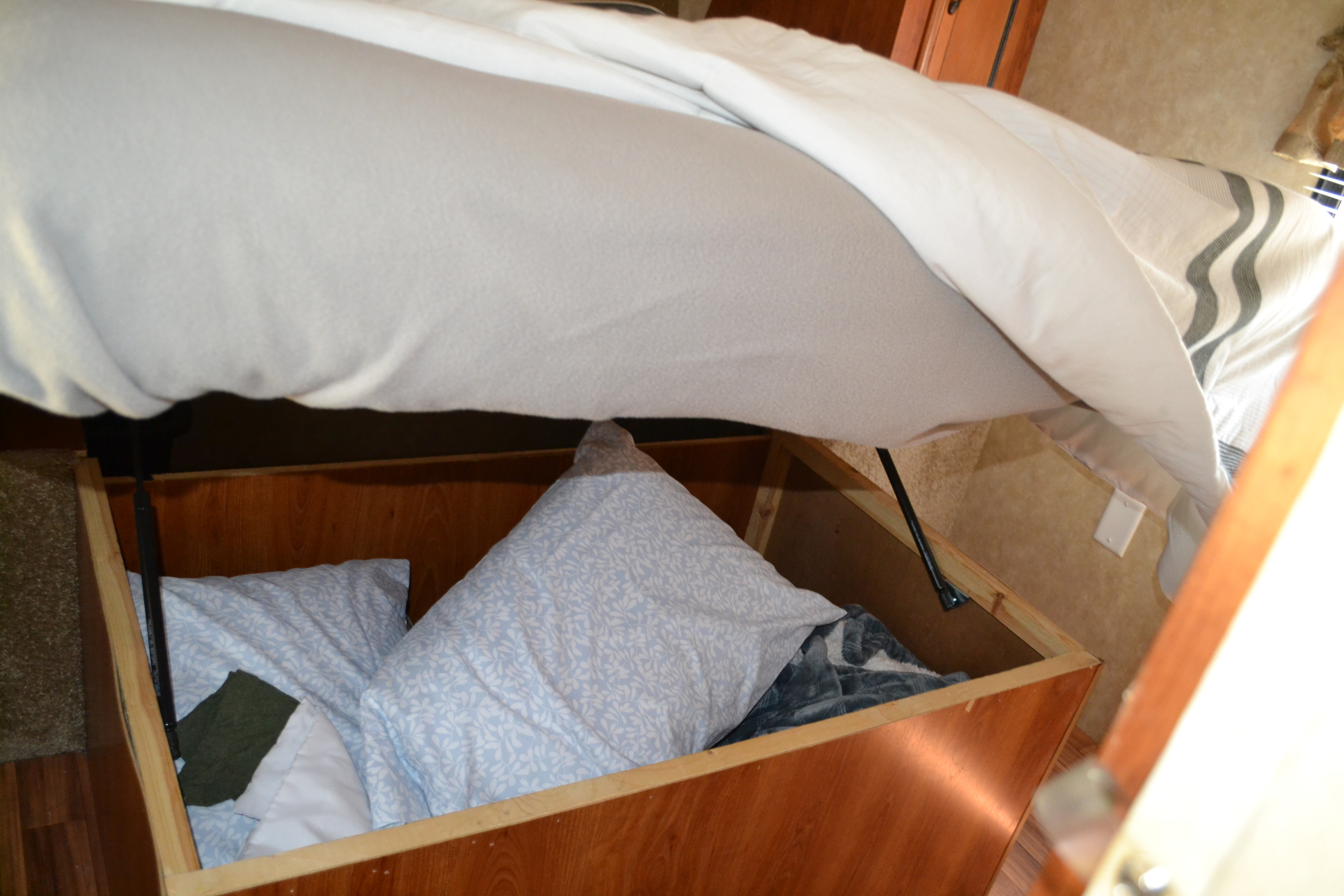 RV rental bed lifted to reveal ample under-bed storage, a smart space-saving solution for travelers. Pillows and blankets stored inside.. Forest River Other 2012