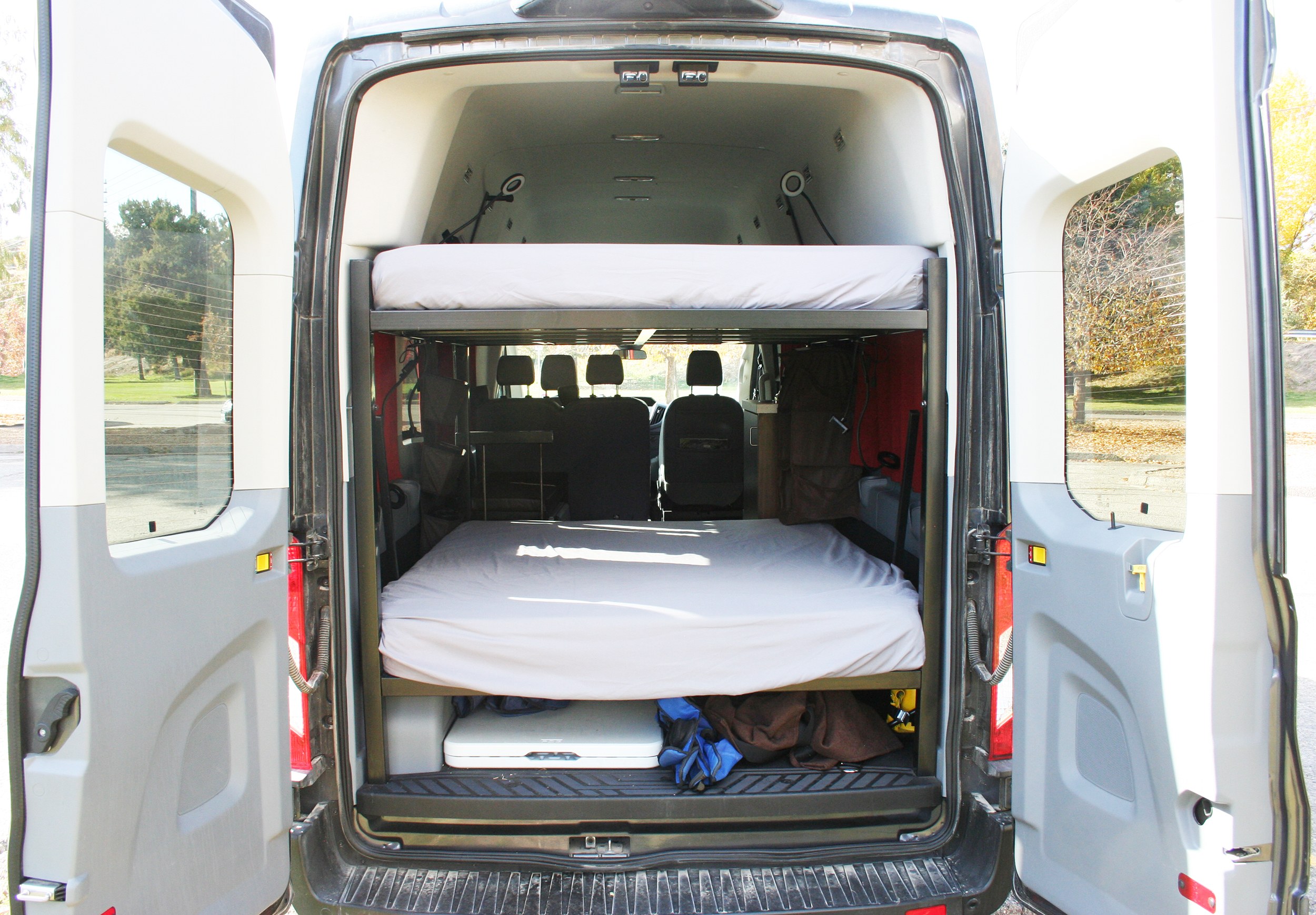 View of an rv rental's spacious camper van interior from the rear, featuring practical bunk beds for comfortable travel.. Ford Transit 2018