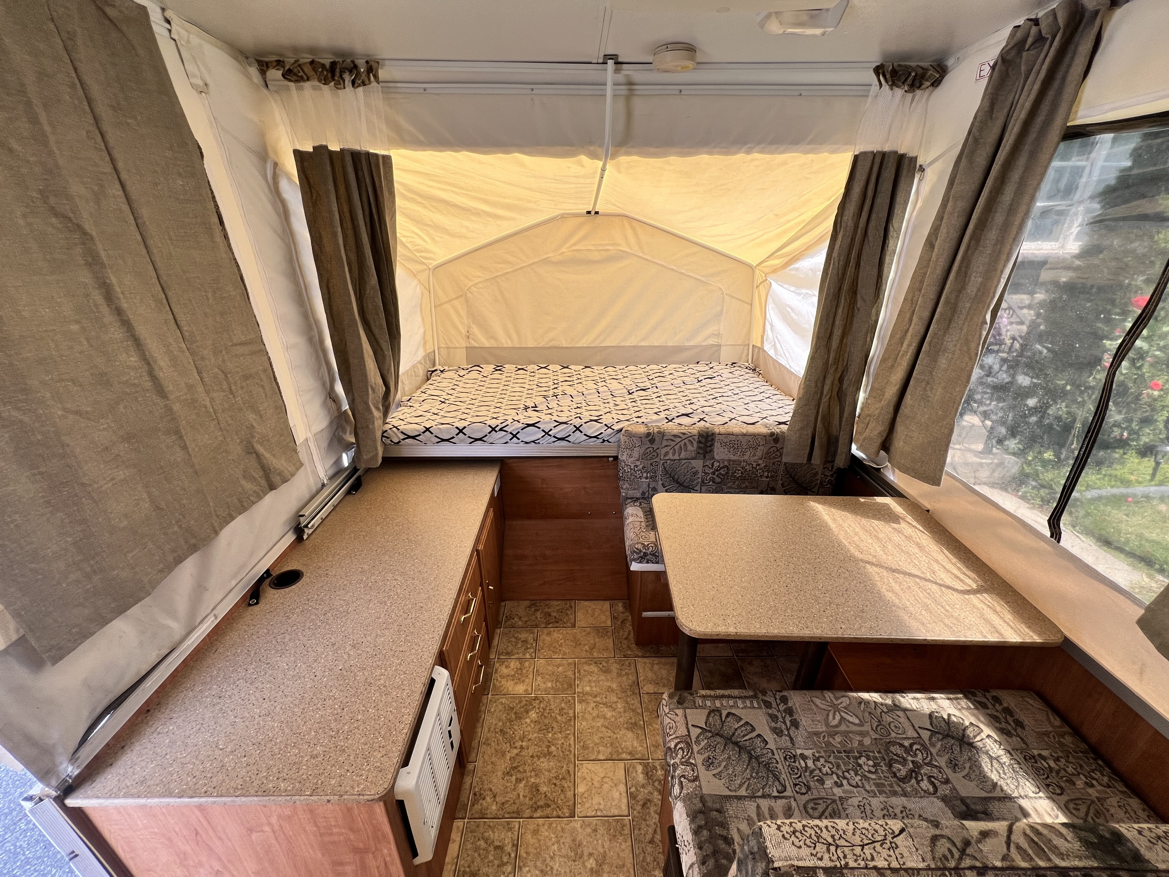 Inside this bright RV rental, a pop-up camper features a rear bed, right dinette, and left kitchenette area.. Forest River Rockwood LTD 2008