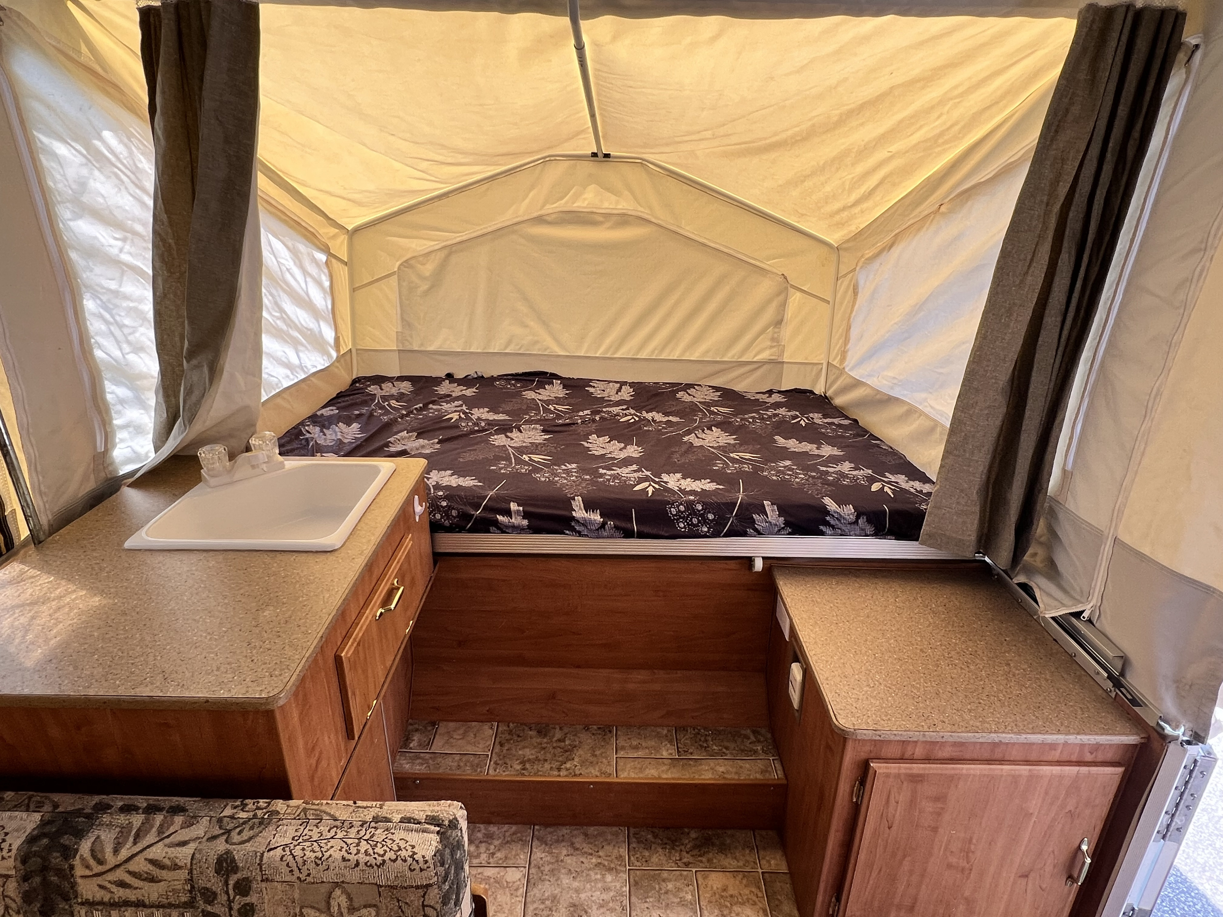 Cozy pop-up camper RV rental interior featuring a bed, sink, and cabinets, perfect for camping.. Forest River Rockwood LTD 2008