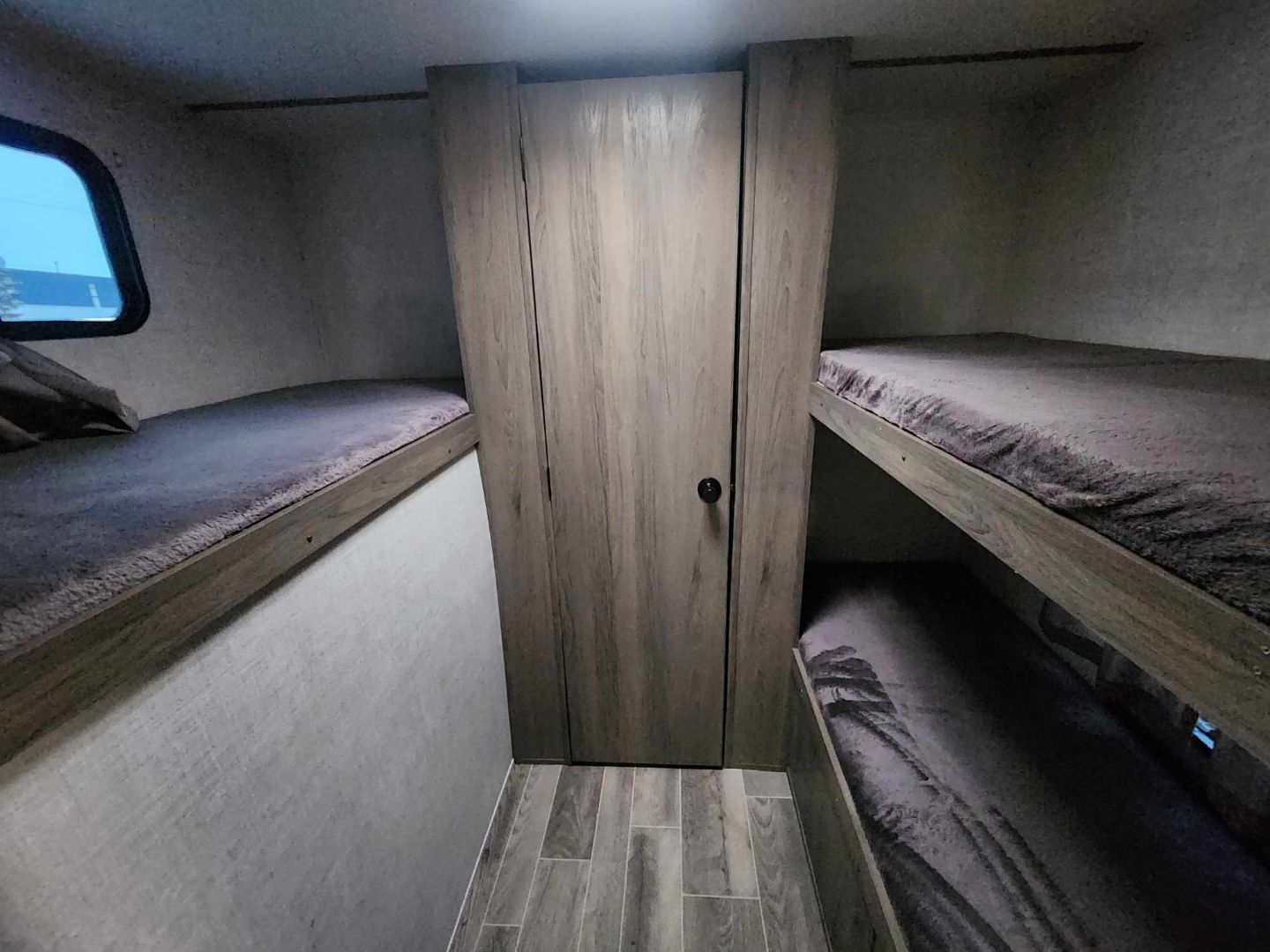 Inside an RV rental, featuring bunk beds on both sides and a central wardrobe. Ideal sleeping for families on the go.. Gulf Stream Trailmaster 2021