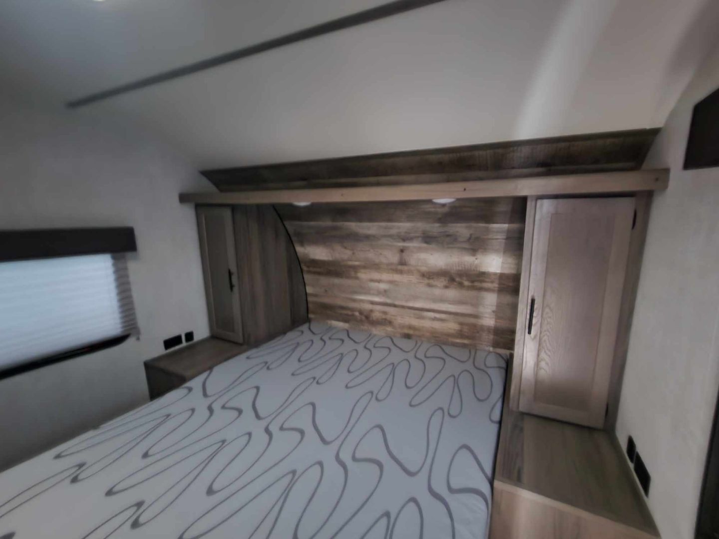 RV rental bedroom interior: a cozy space with a patterned bed, wood headboard, and built-in storage in a travel trailer.. Gulf Stream Trailmaster 2021