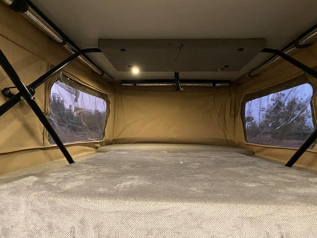 RV rental's pop-up tent interior: a cozy sleeping area with light tan fabric walls, sturdy supports, and clear windows overlooking nature.. Mercedes-Benz Sprinter 2017